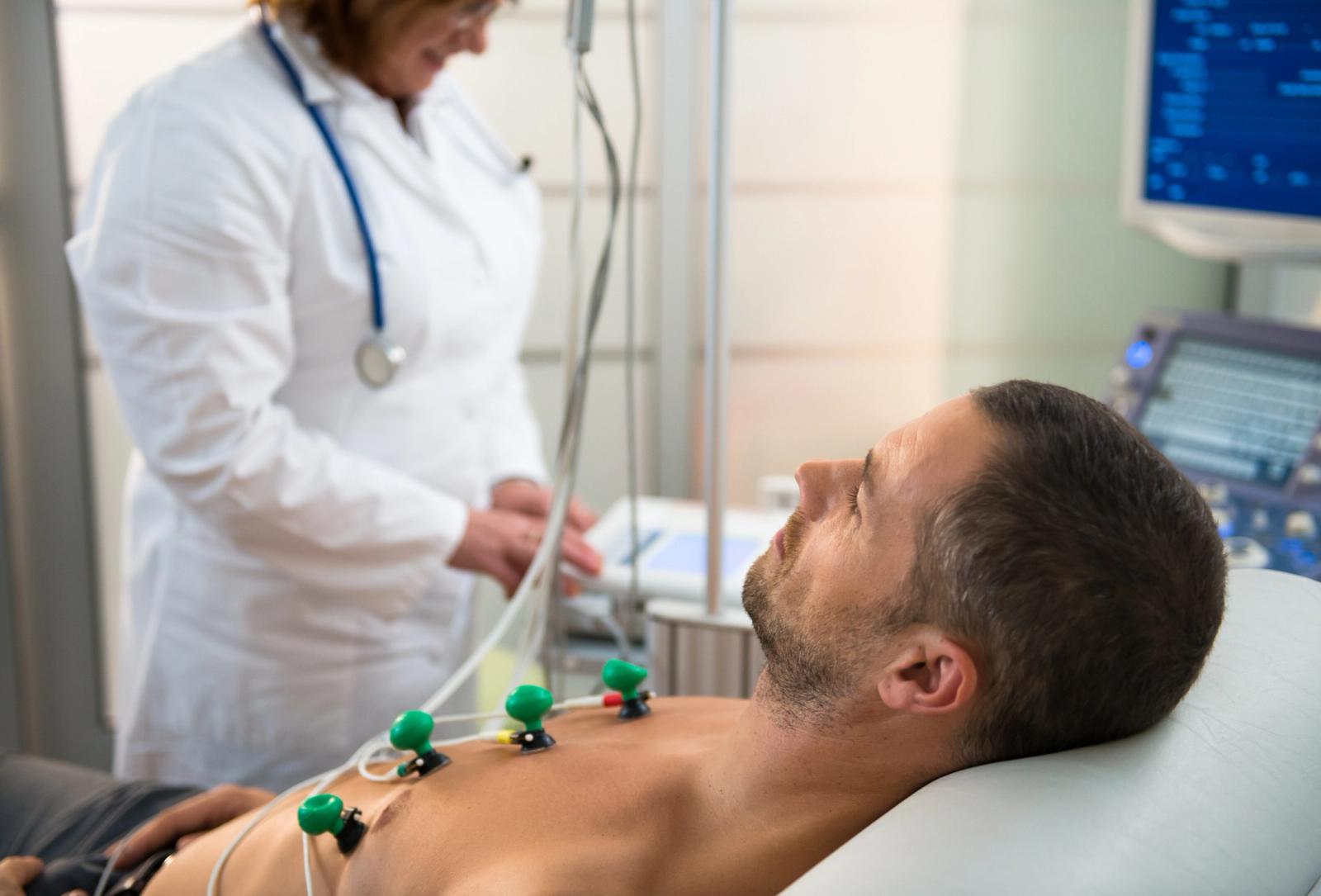 Patient lying on a couch with ECG electrodes attached to the chest in a clinical setting