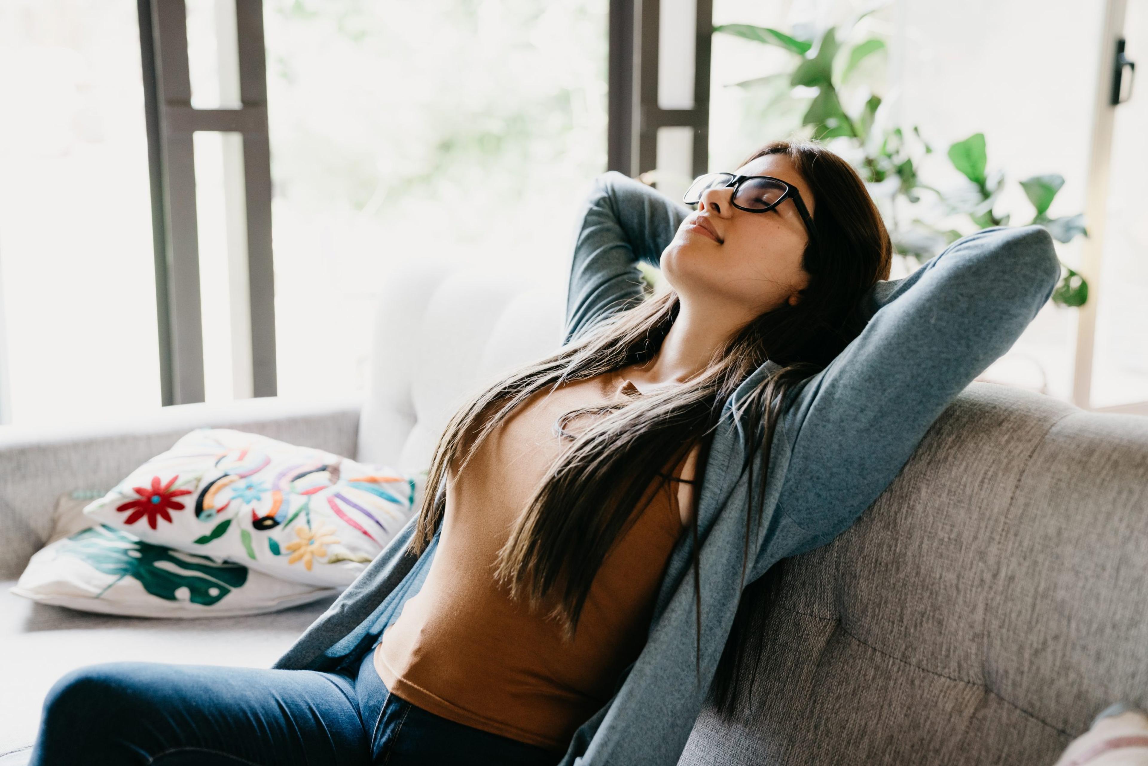 Young adult woman relaxing at home, sitting on the sofa