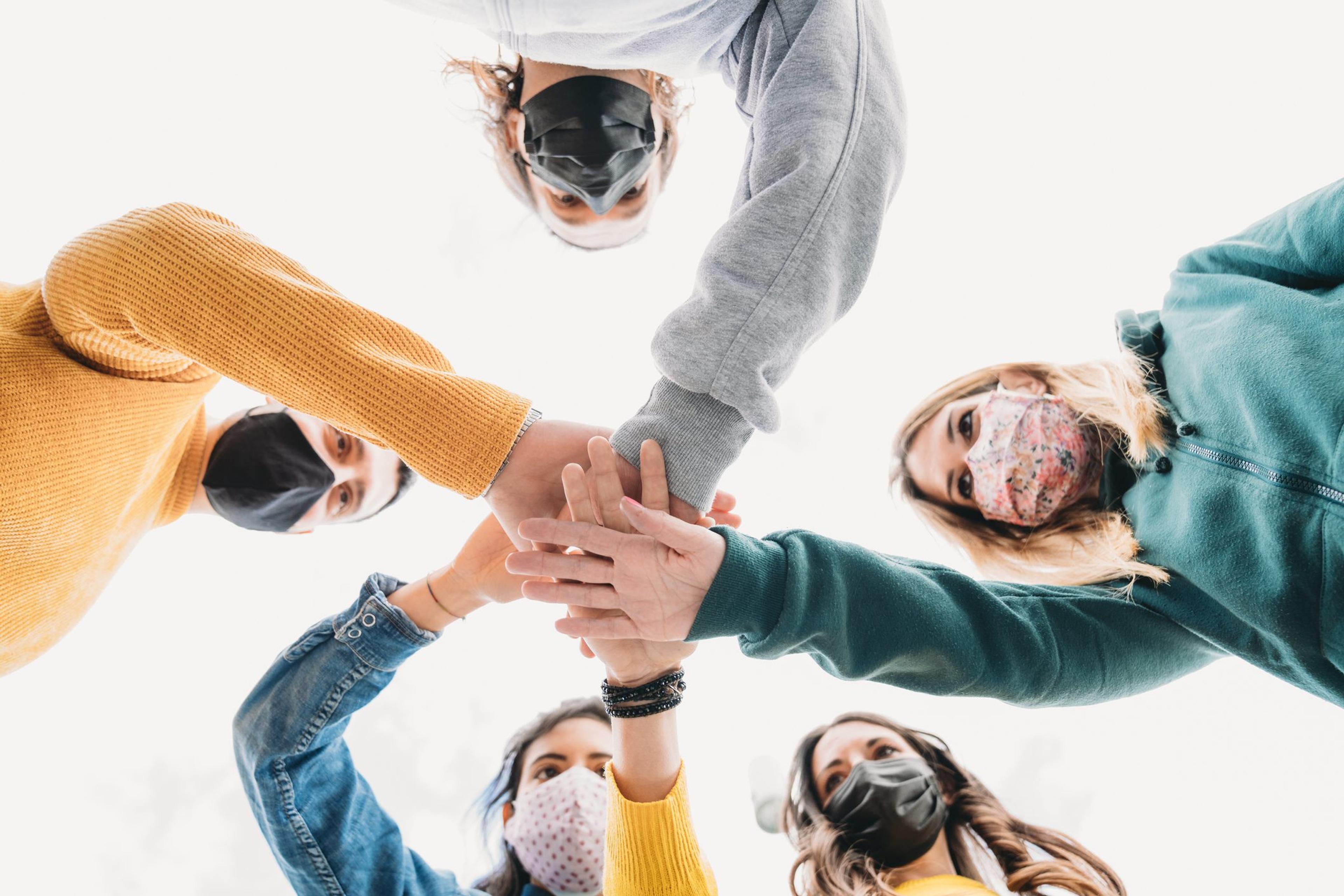 Millennial friends stacking hands together - View from below