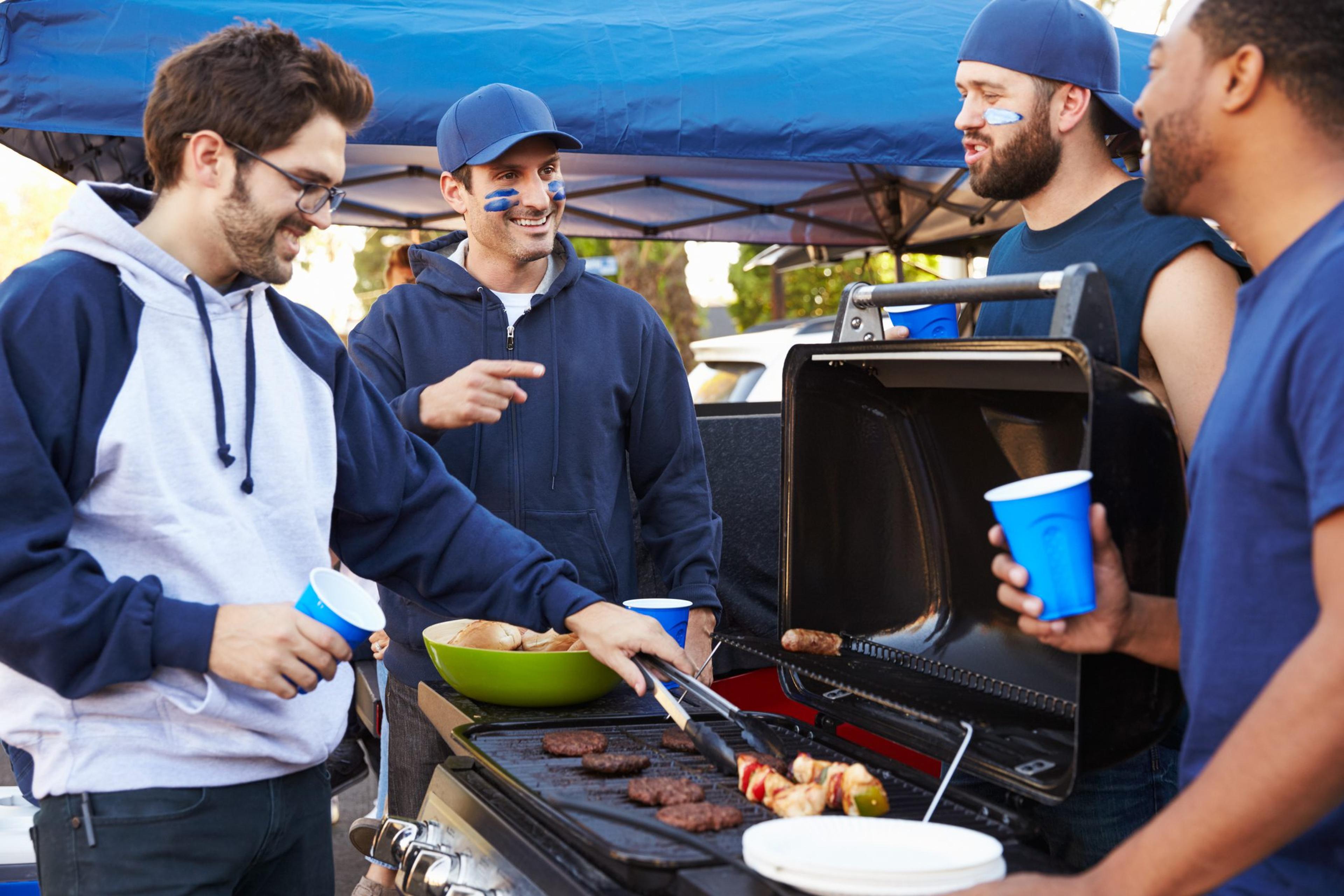 Group Of Male Sports Fans Tailgating In Stadium Car Park