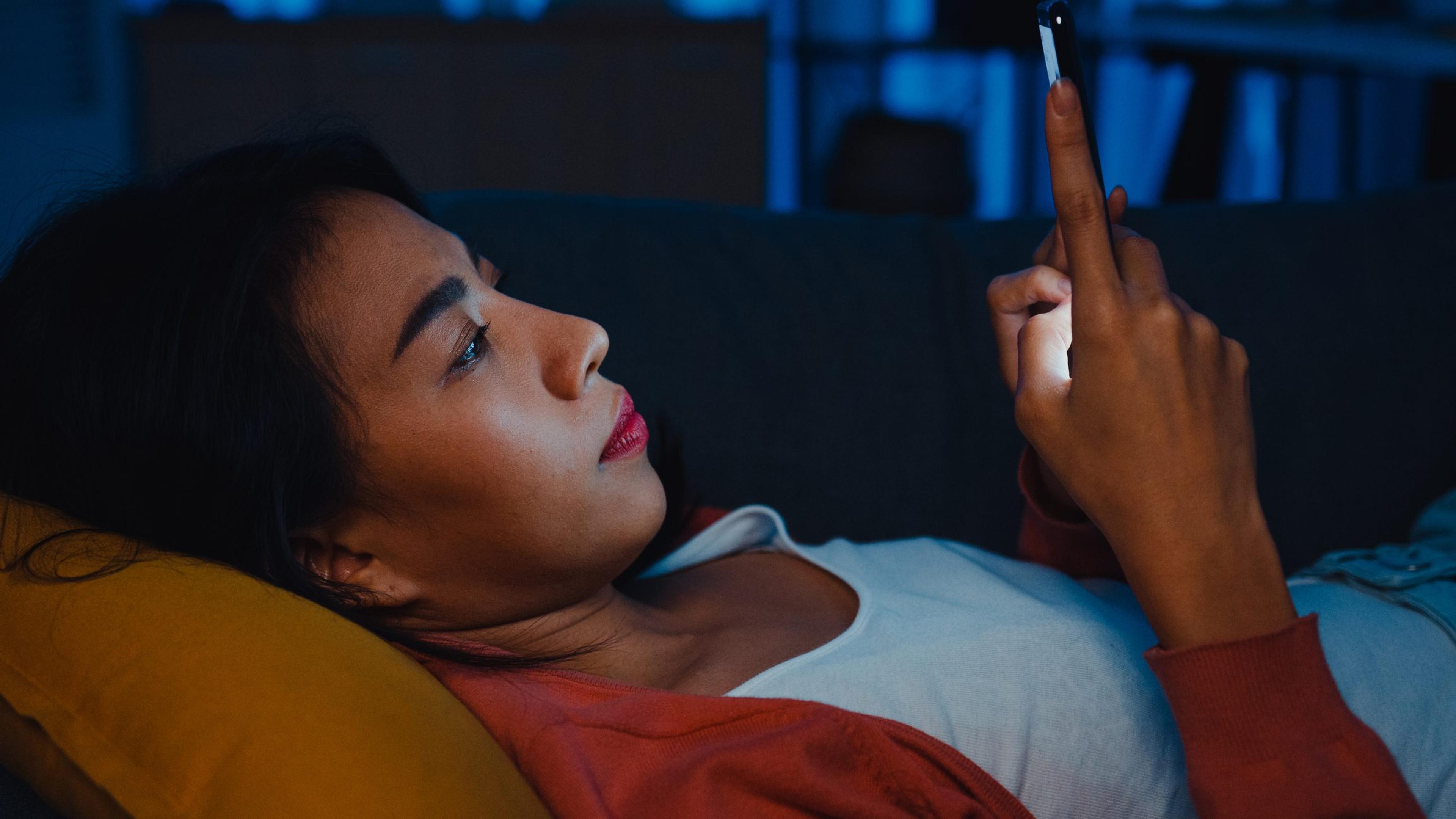 Young woman looks at her phone at night