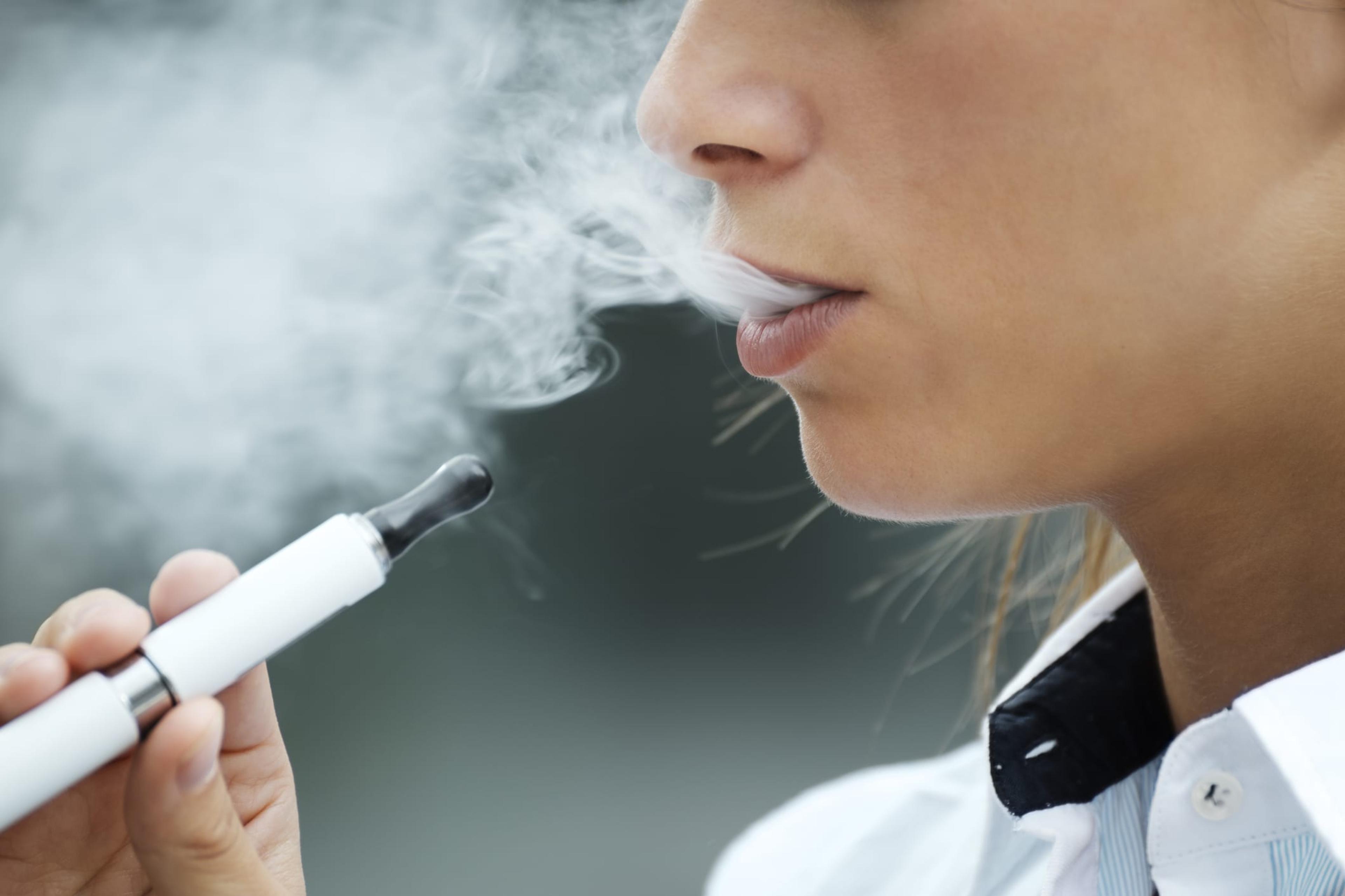 Woman using an electronic cigarette and blowing a cloud of vapor
