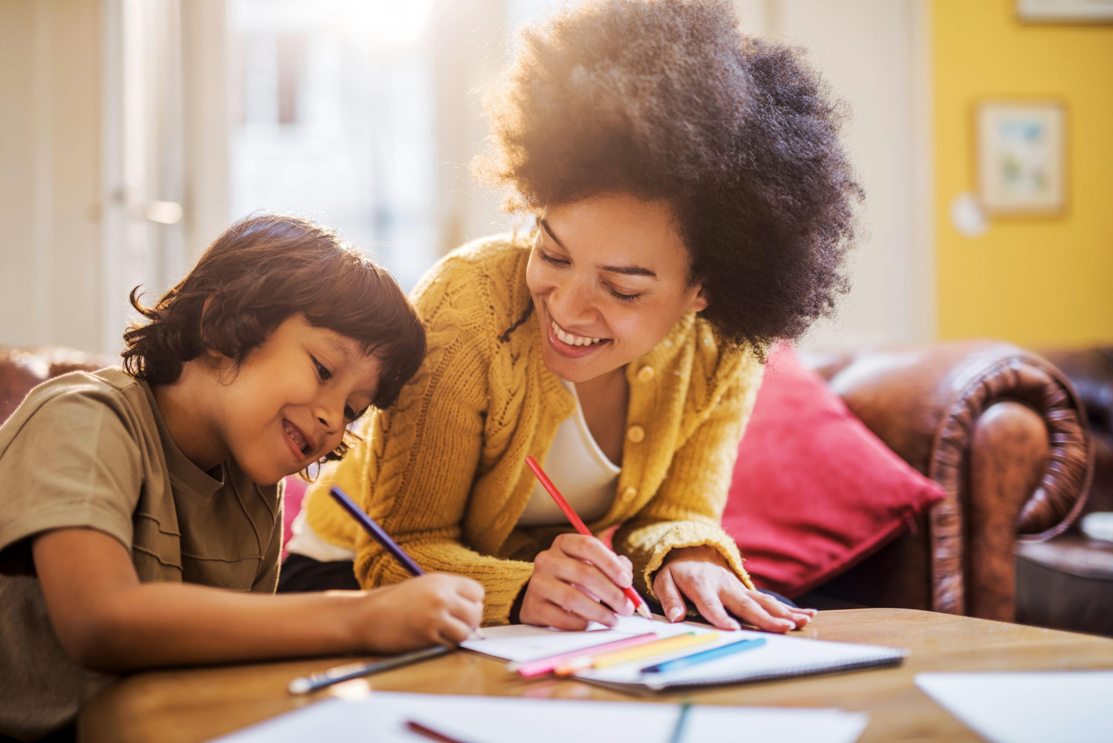 Smiling African American mother and son coloring together.