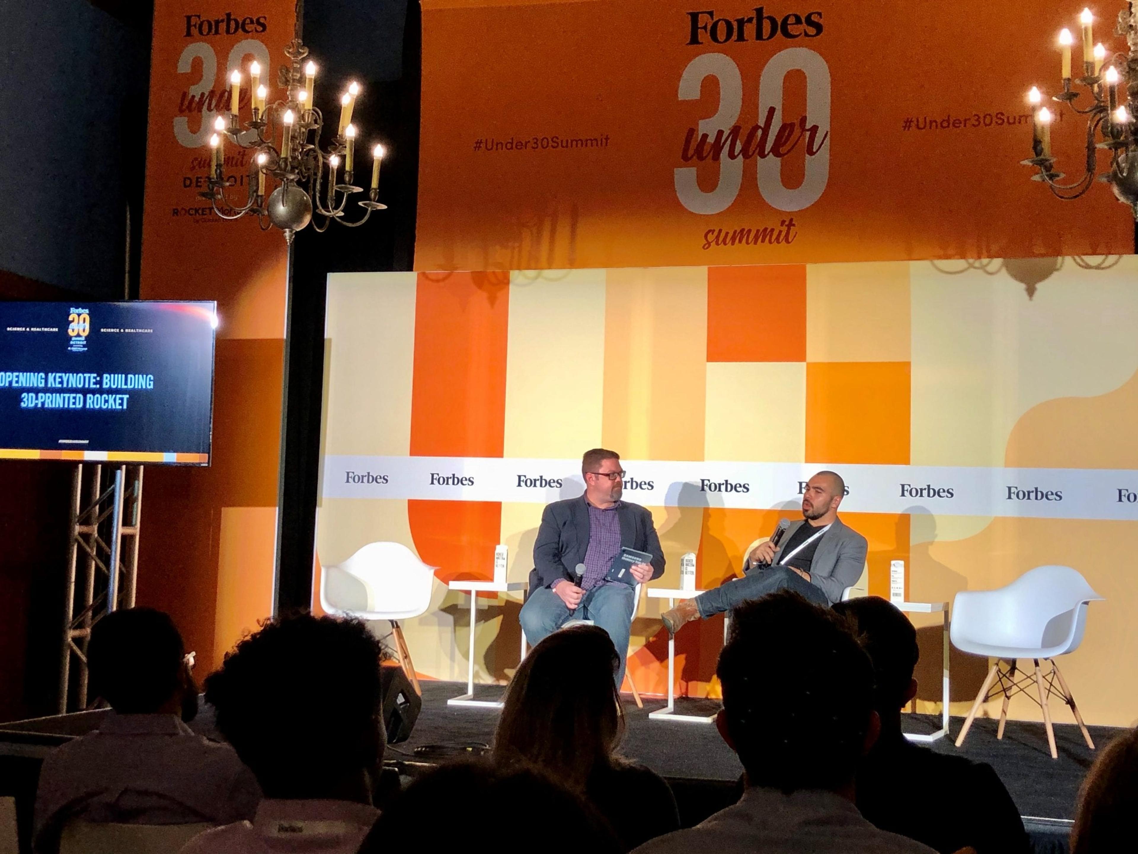 Two men interview each other on stage at the Forbes Uner 30 Summit
