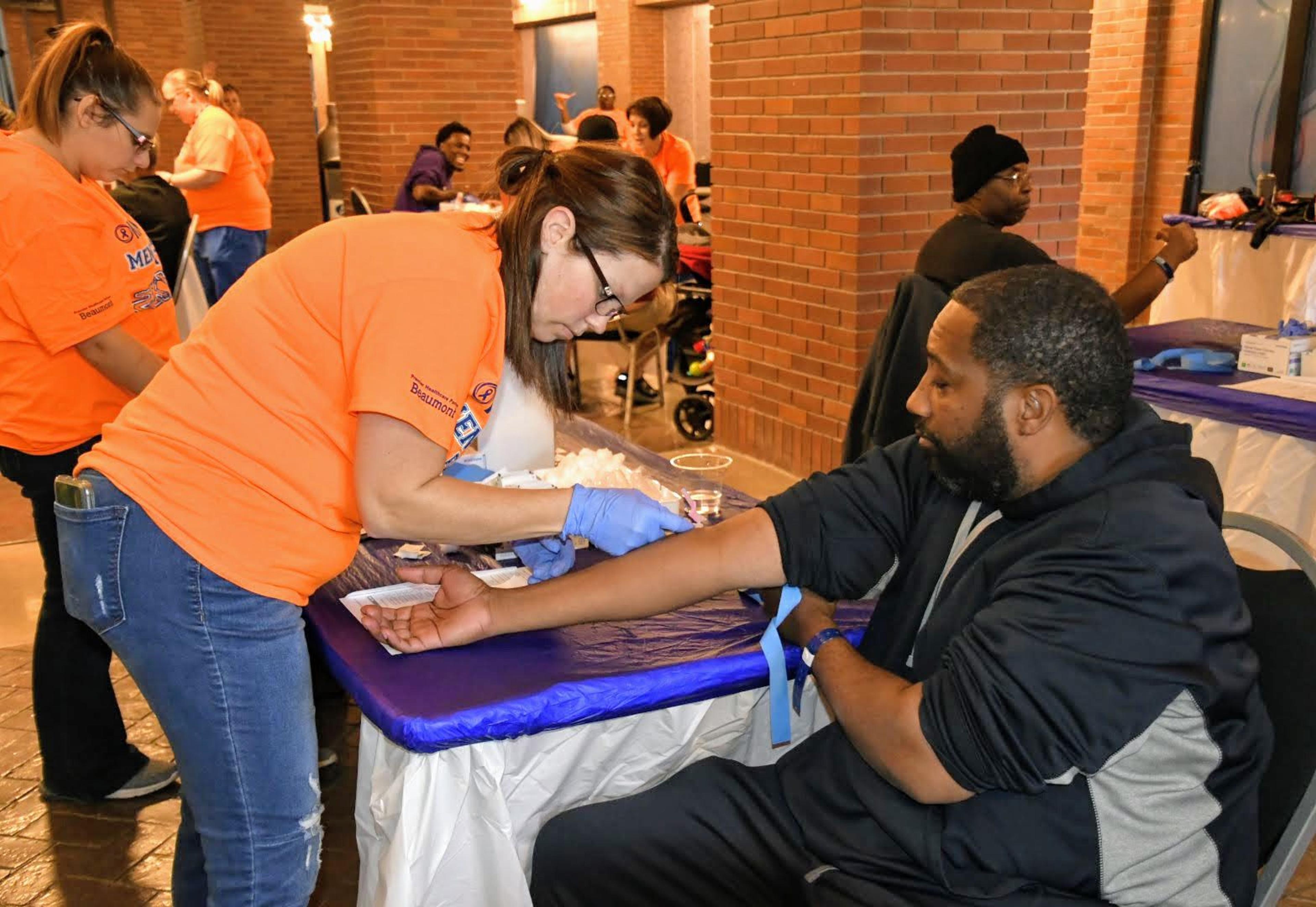 A nurse draws blood from a middle age man at the Men's Health Event