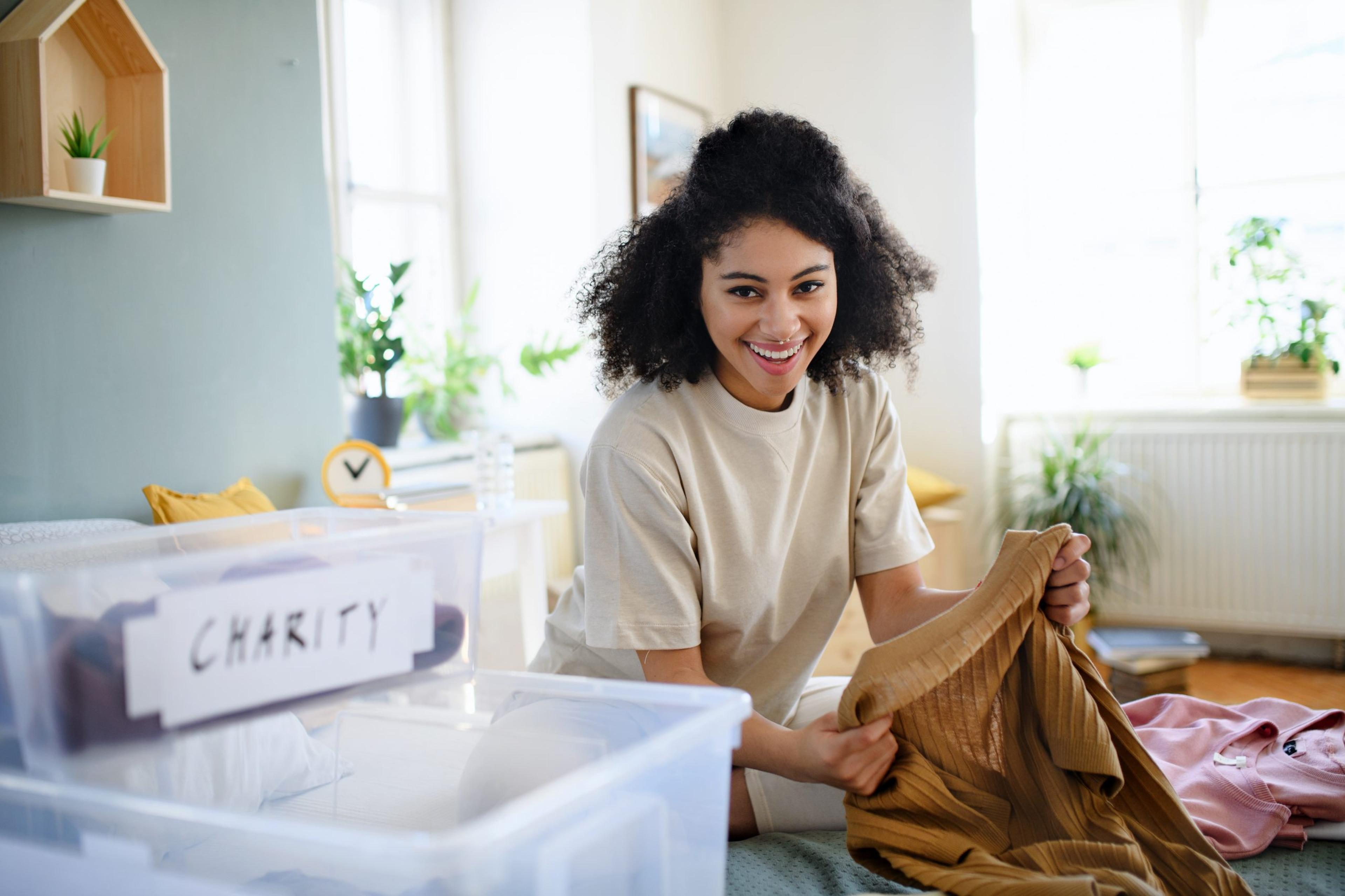 Young woman sorting wardrobe indoors at home, charity donation concept.