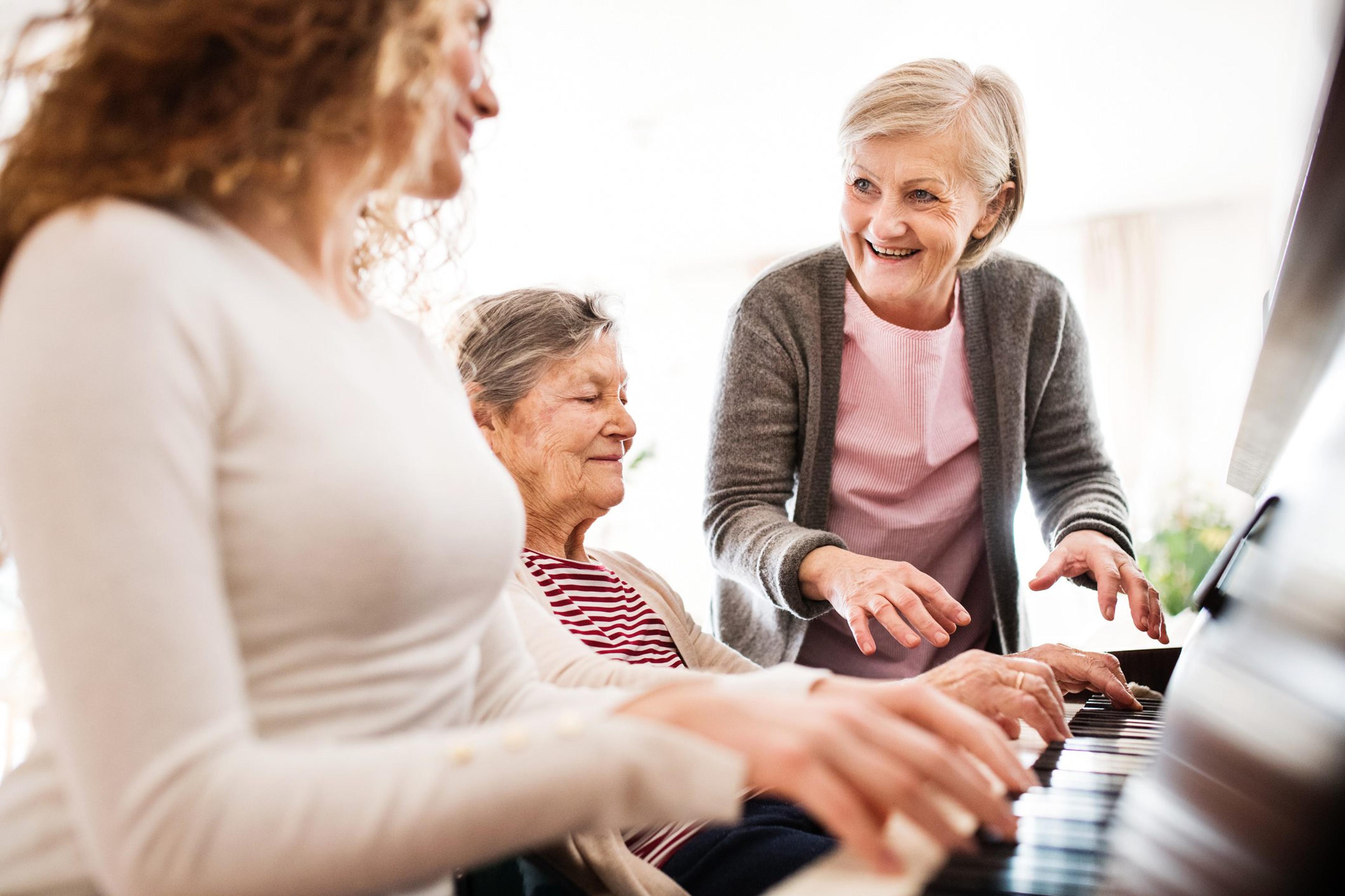 Older mother and grandmother playing piano with teenage daughter