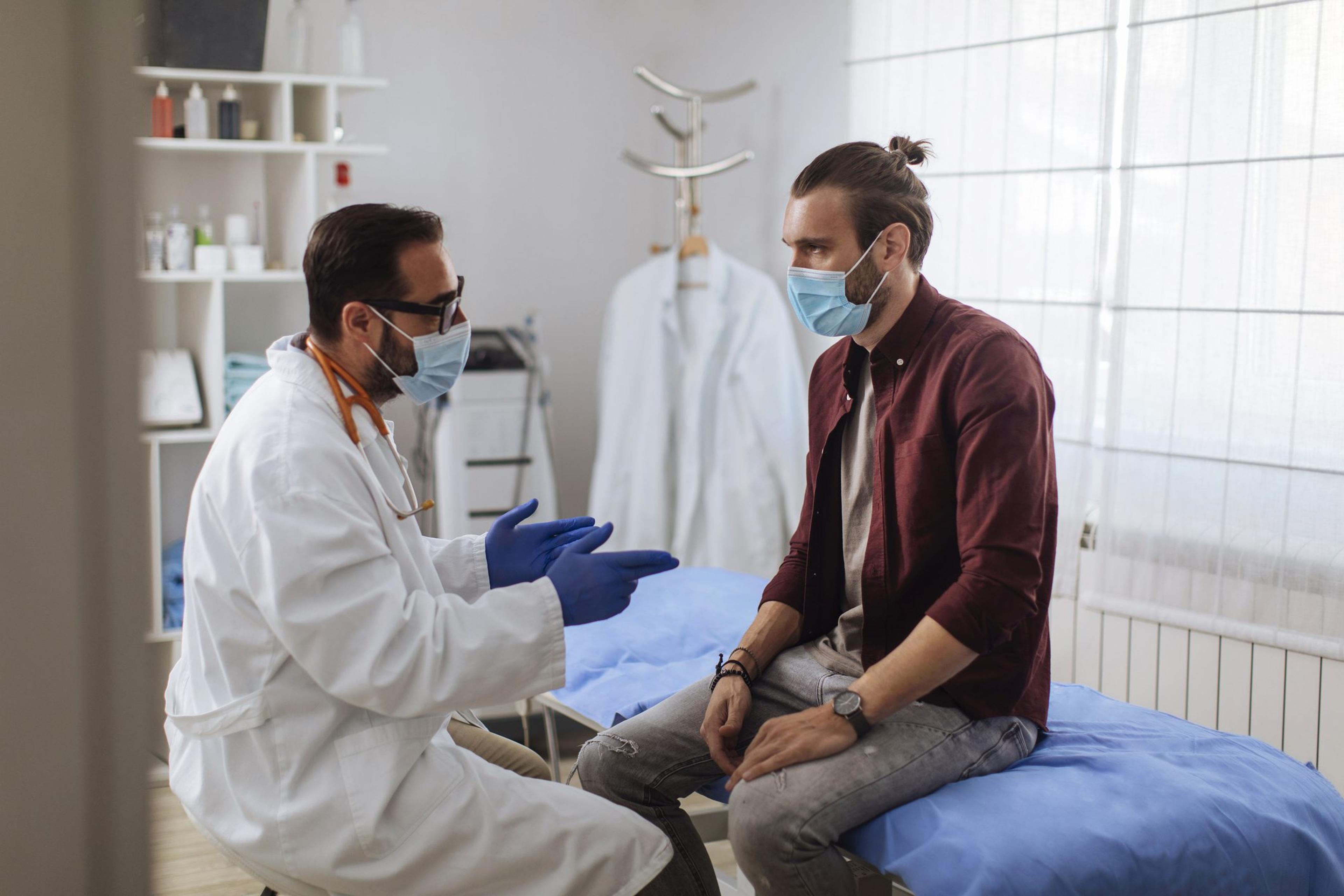 Man wearing a mask talks with his doctor