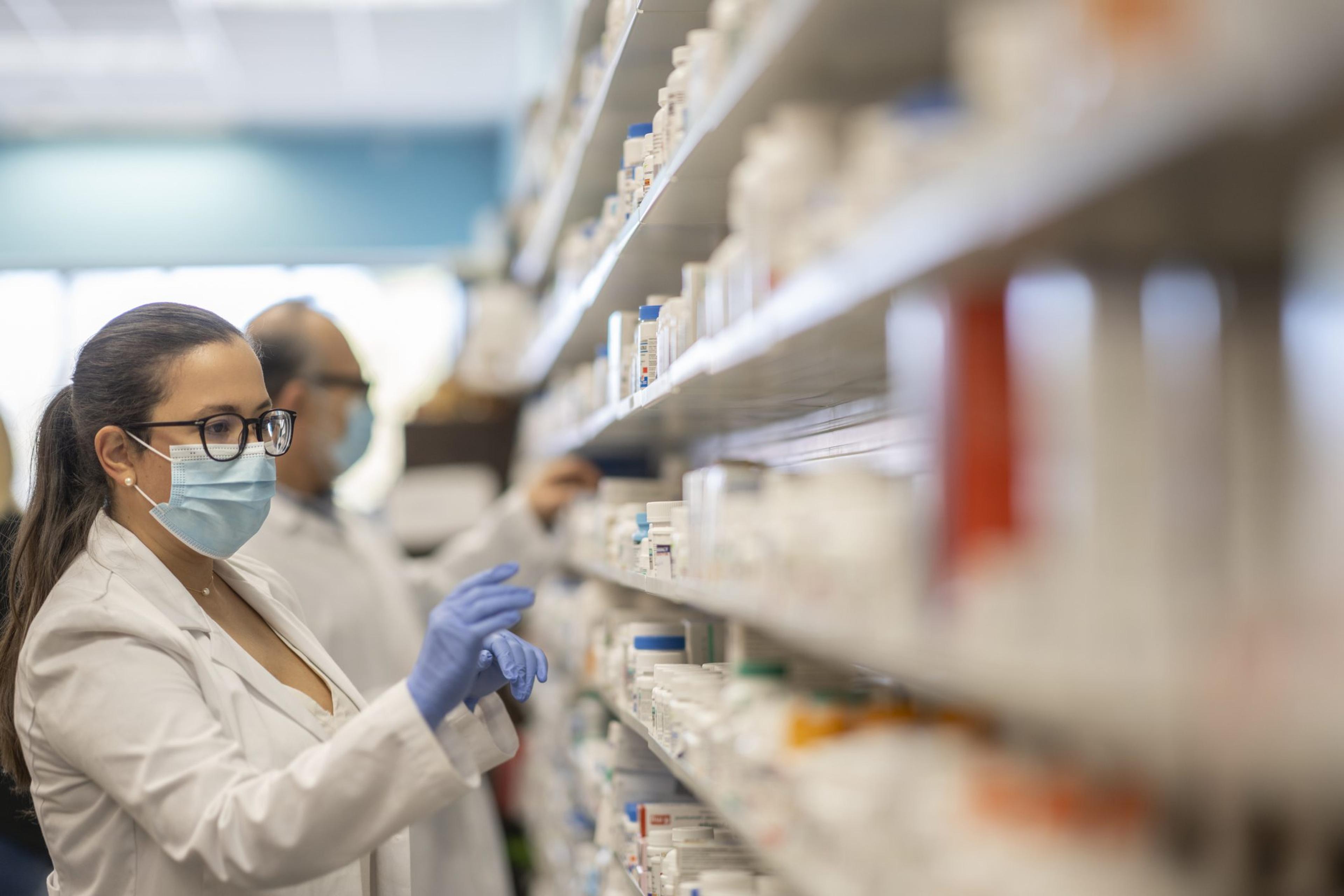 Female pharmacist wearing a mask sorting medications