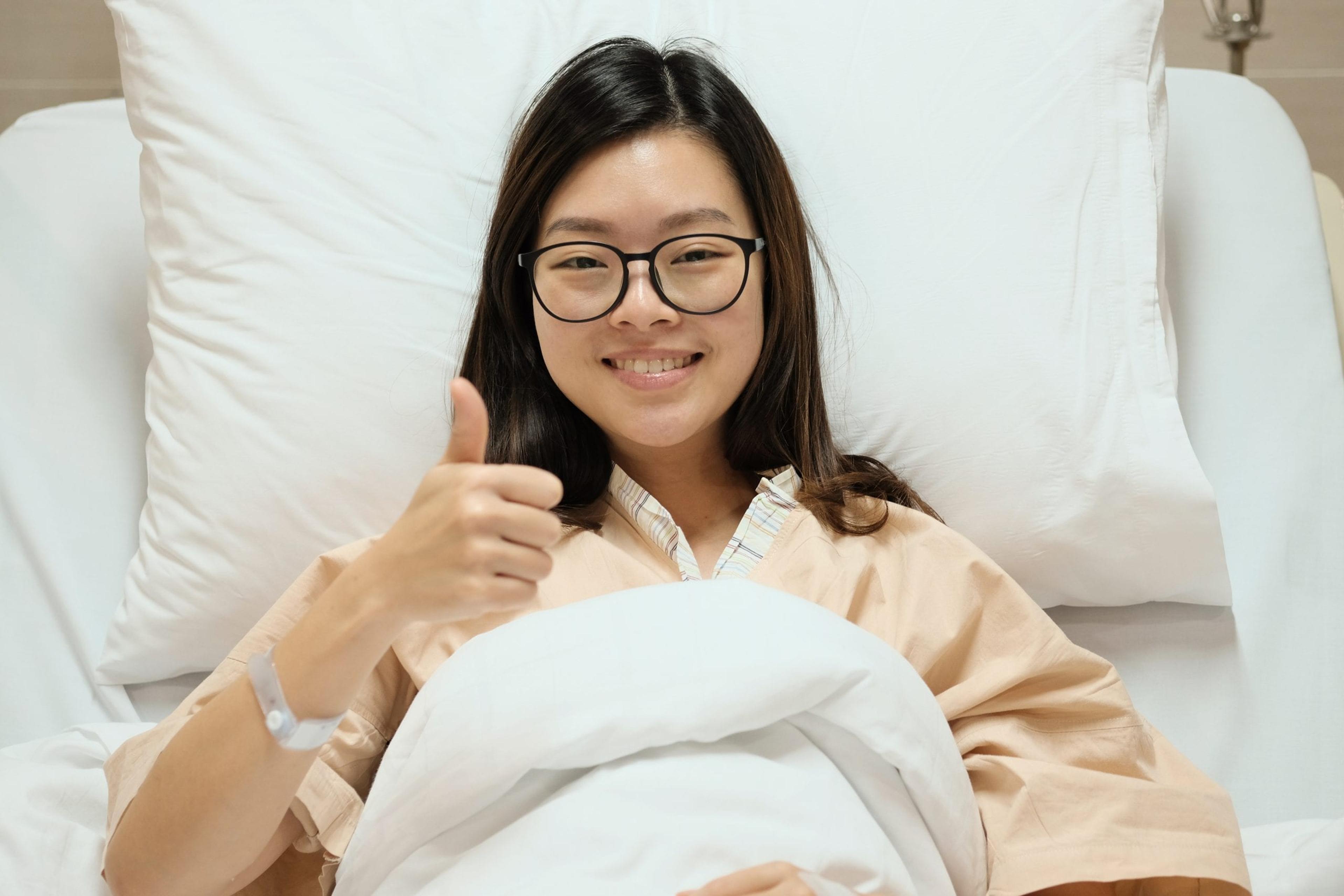 Image of a patient in a hospital bed giving a thumbs up.