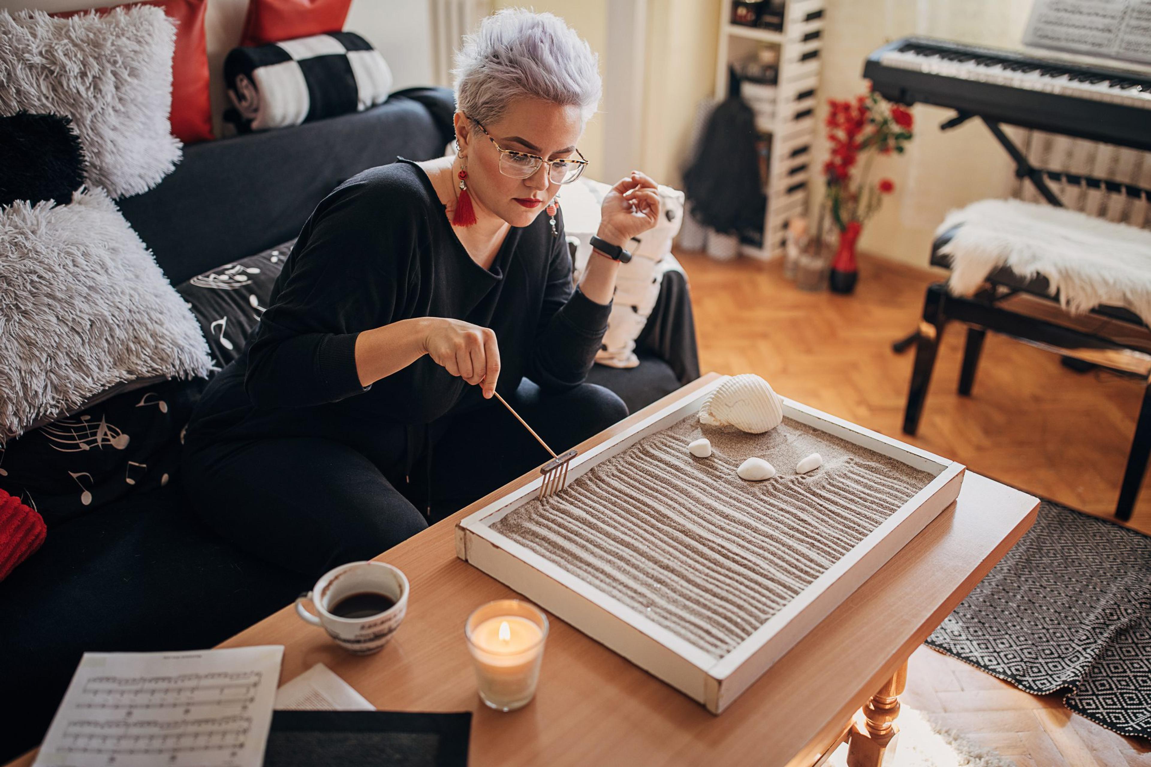 Woman sitting on the ground using a zen garden on the coffee table
