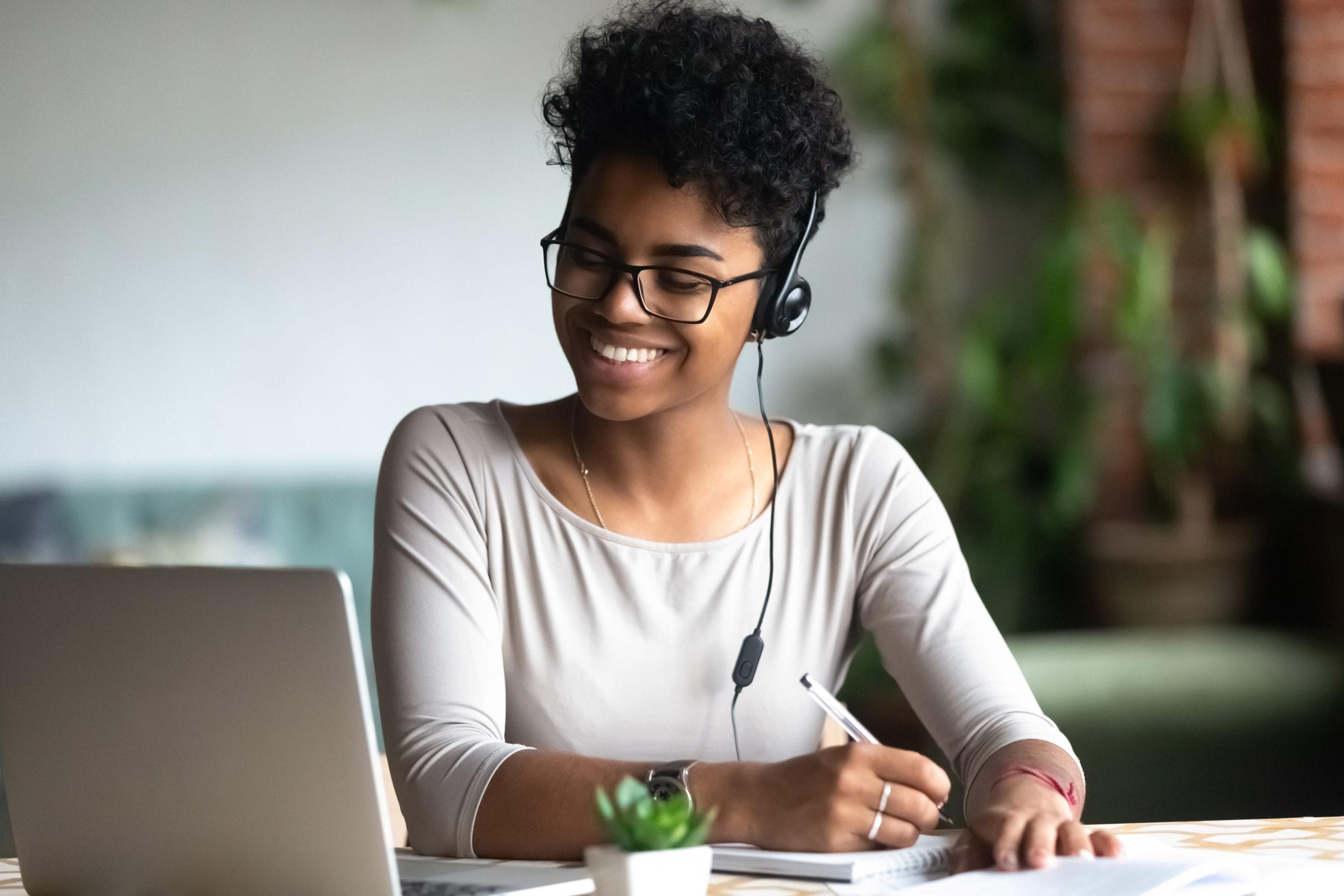 Woman taking notes watching her computer