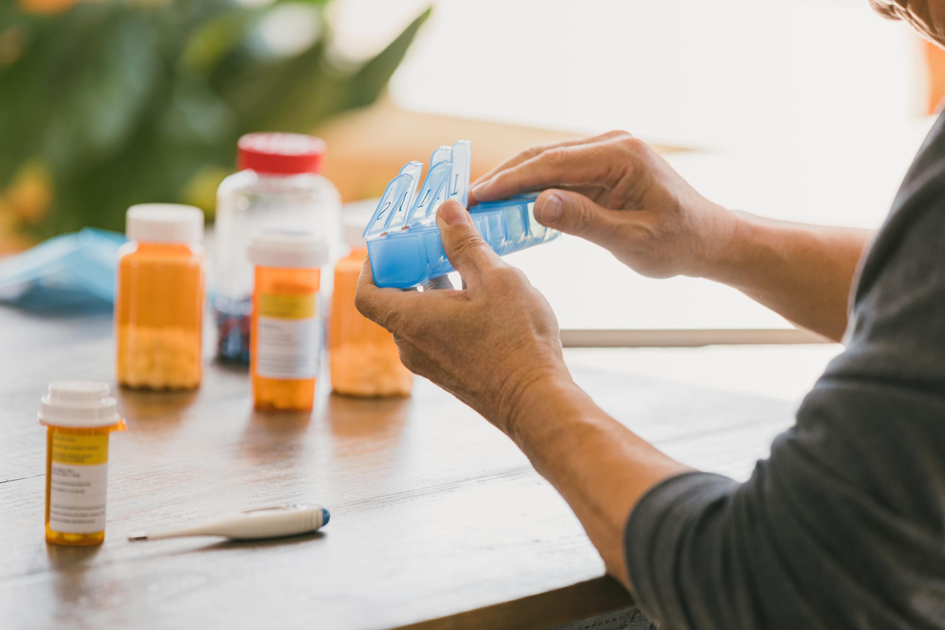 Man organizes his medications in his pill box