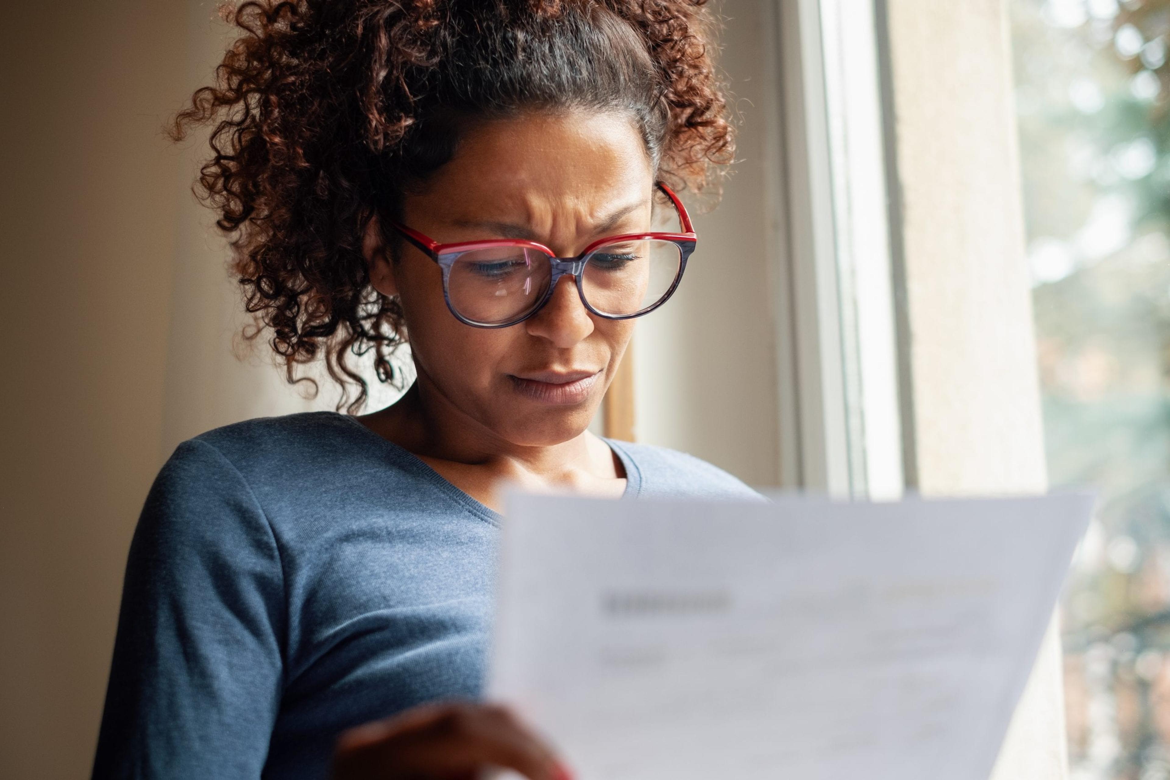 Woman reading a bill with confused look on her face