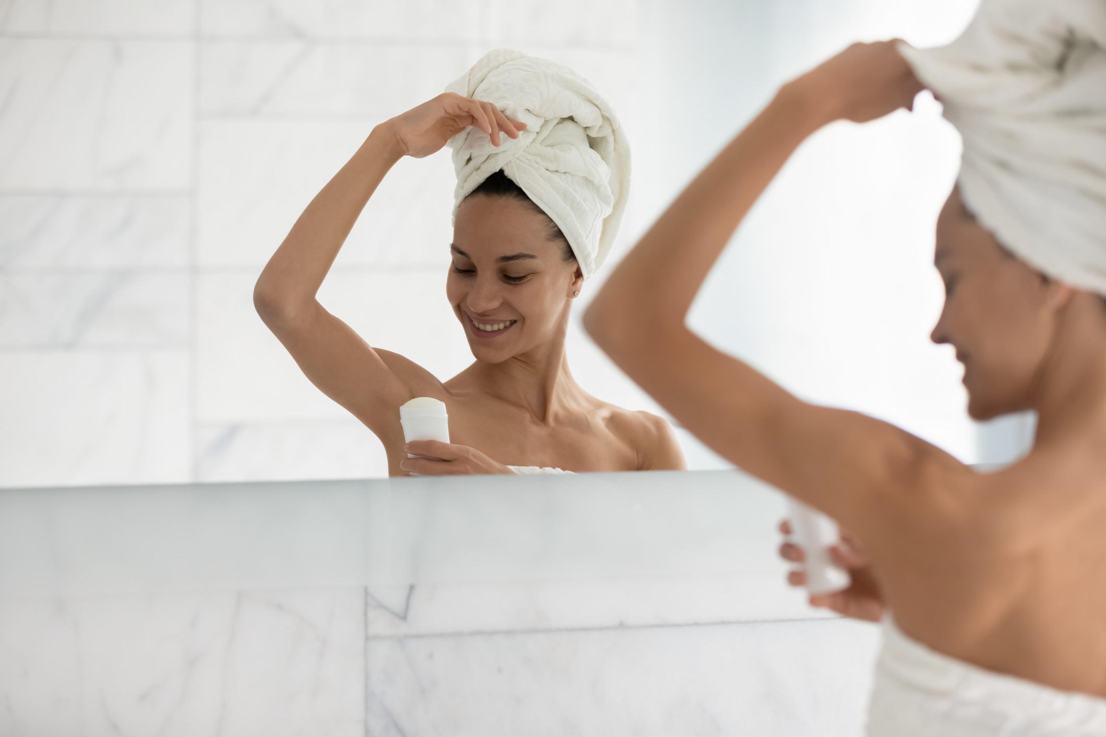 Woman wearing towels puts on deodorant