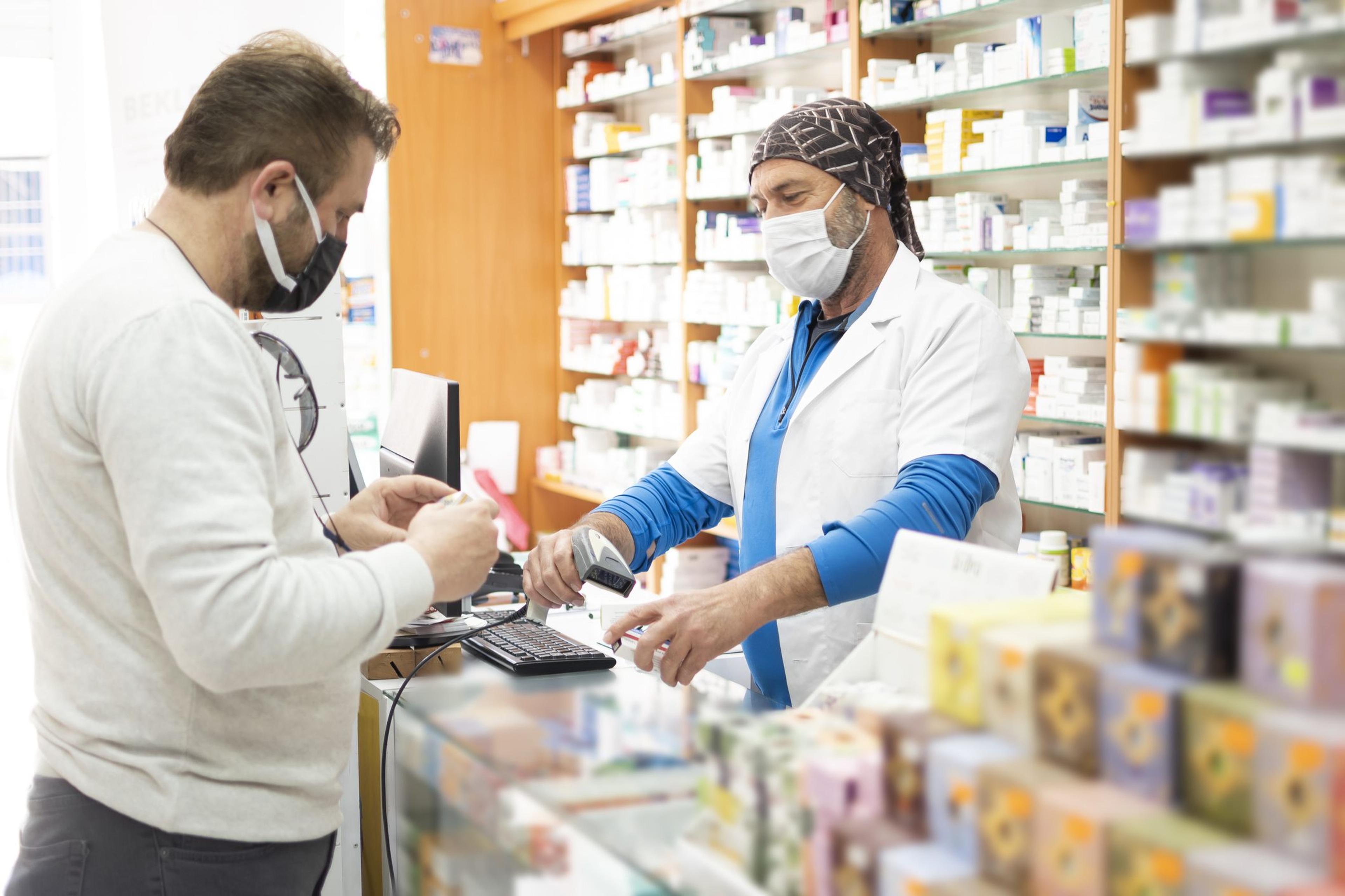 Pharmacist wearing protective hygienic mask and making drug recommendations in modern pharmacy