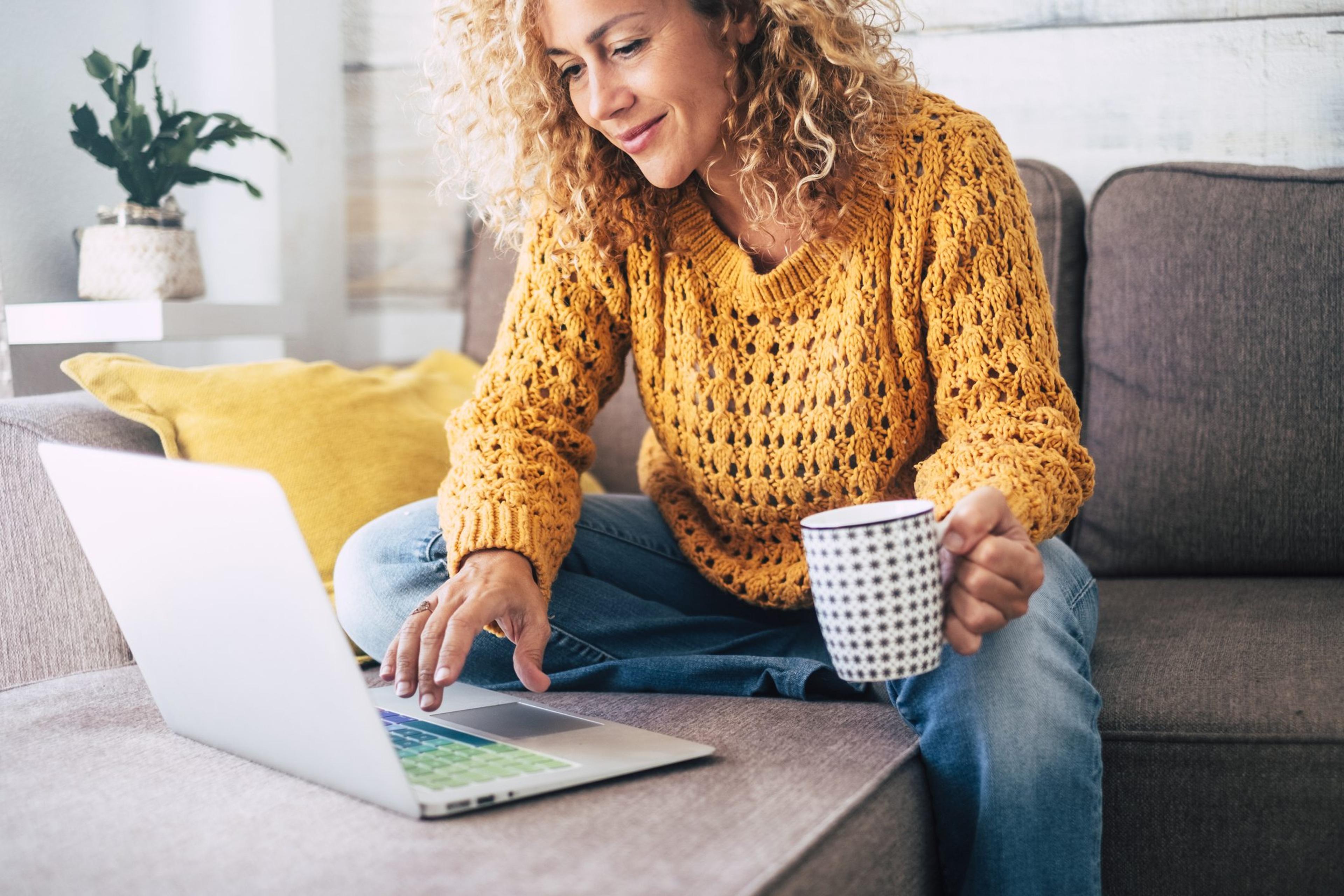 Woman uses her laptop while sitting on her couch working online