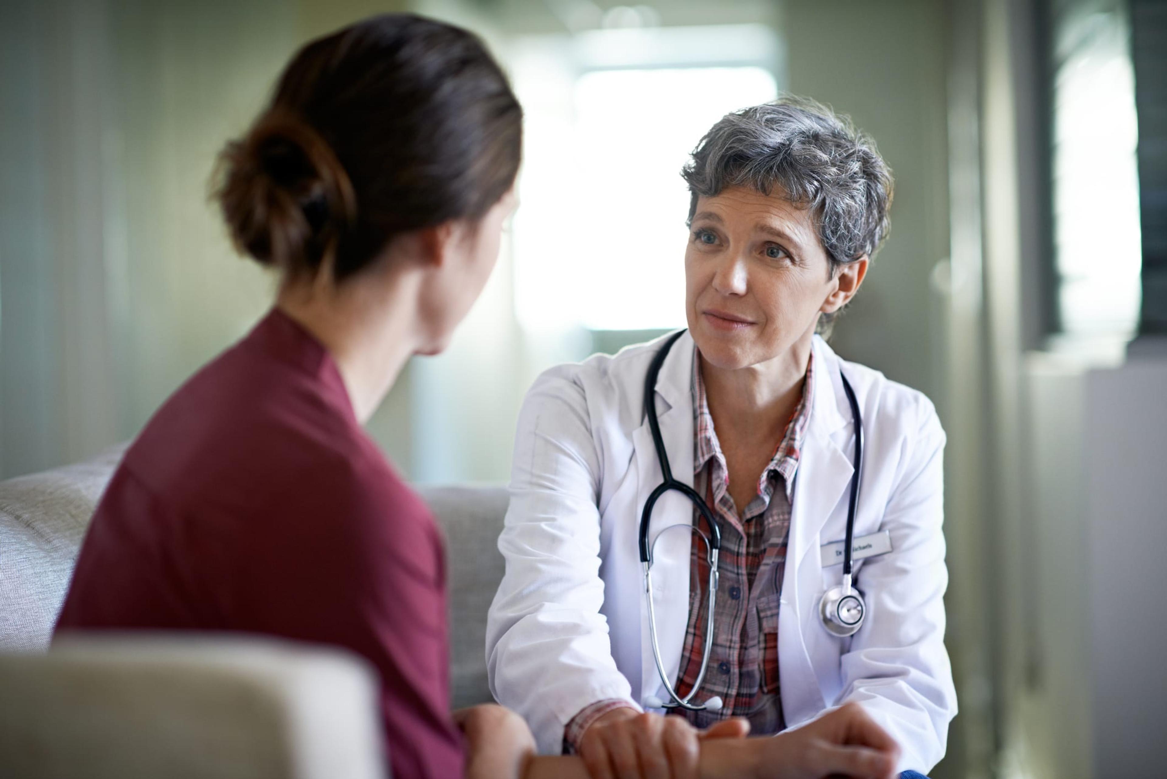 Photo of a compassionate doctor comforting a young woman in a hospital waiting room