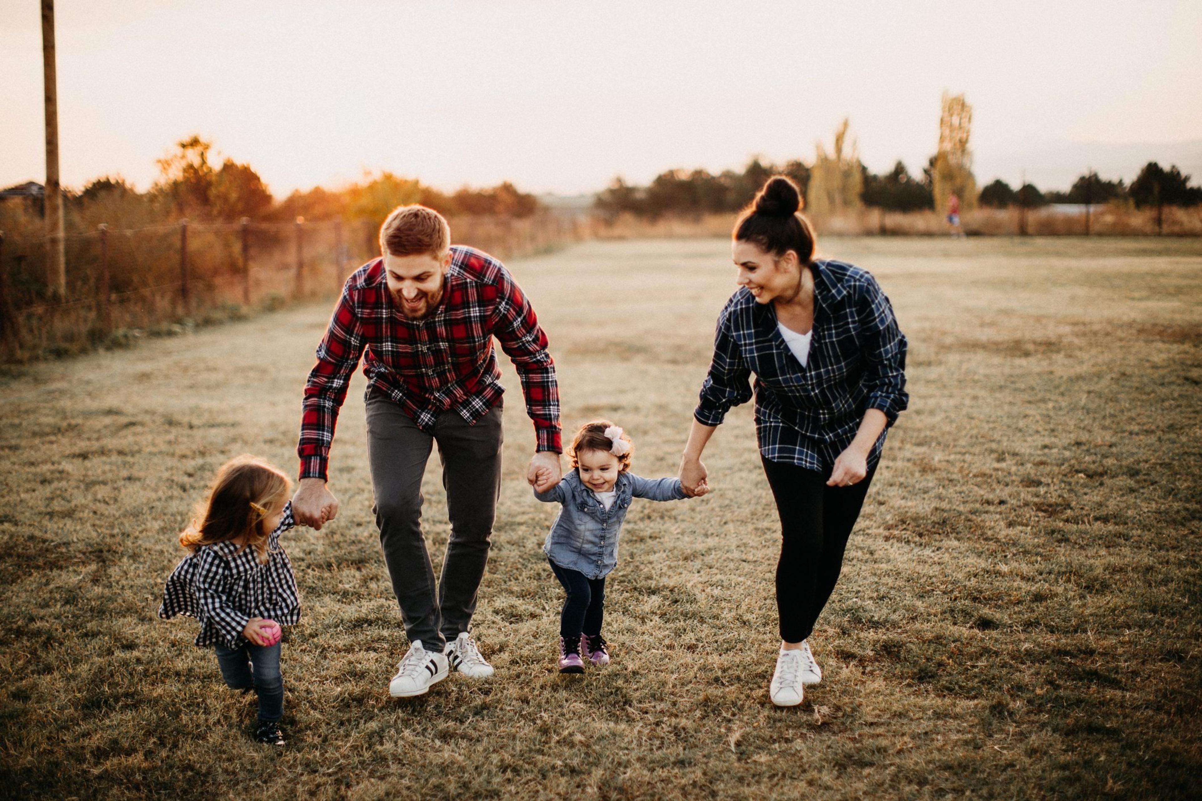 Parents carrying kids, playing in meadow