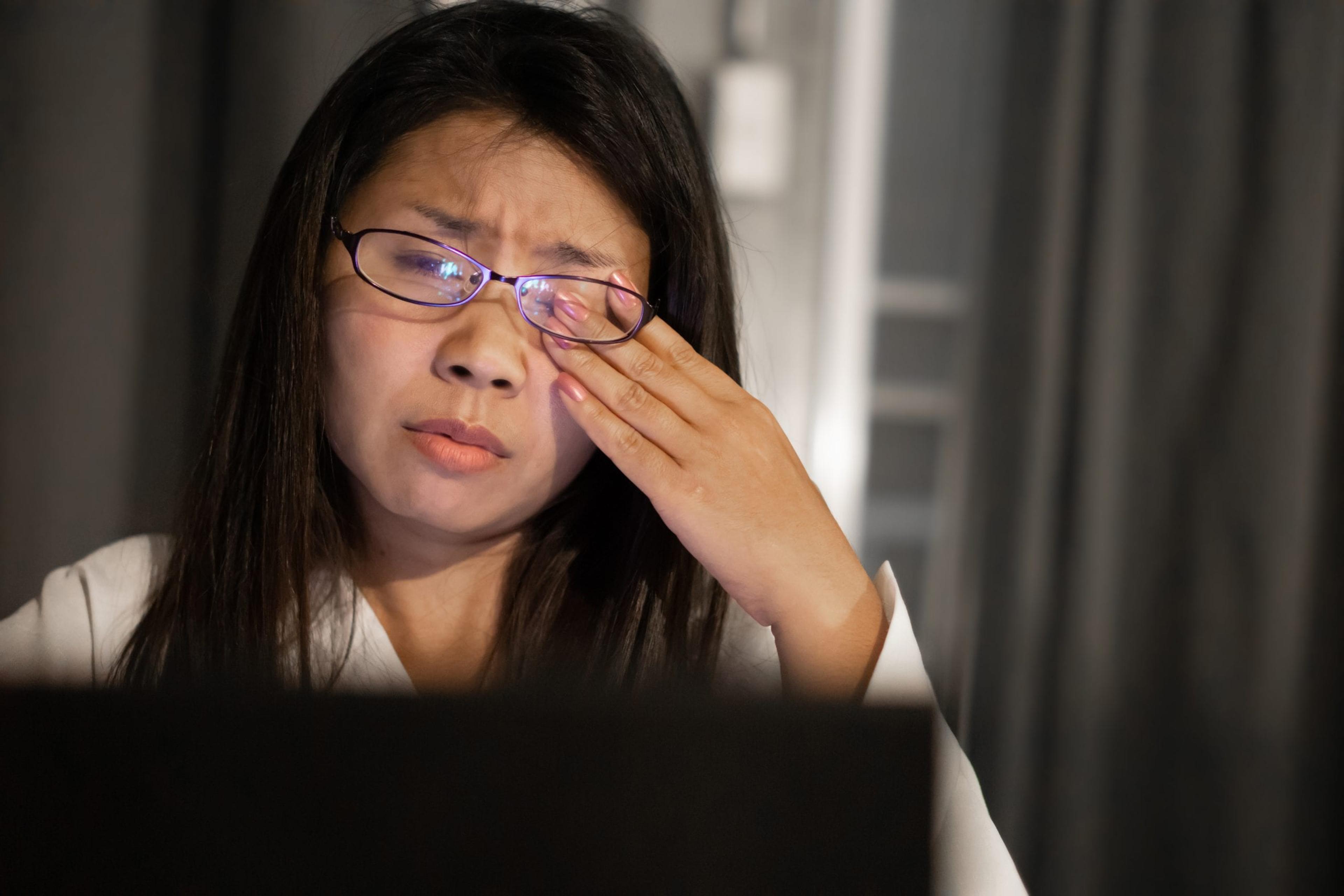 Asian woman suffering from eye strain tired from overwork on computer screen