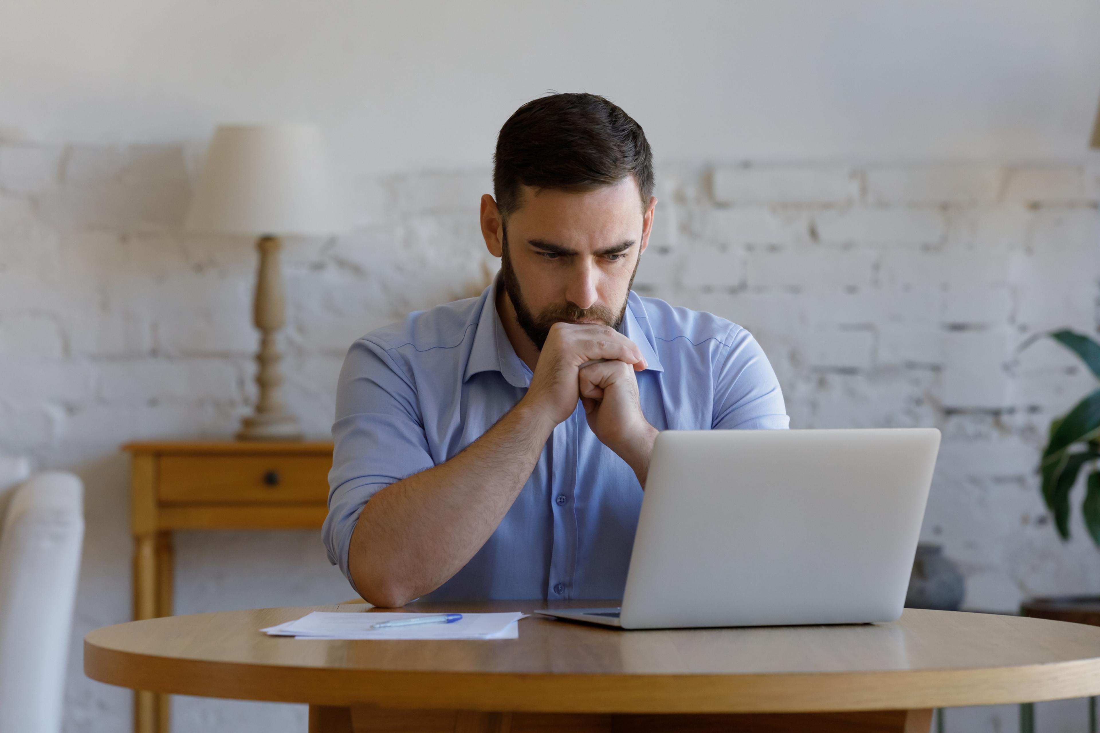 A man stares at his laptop screen.