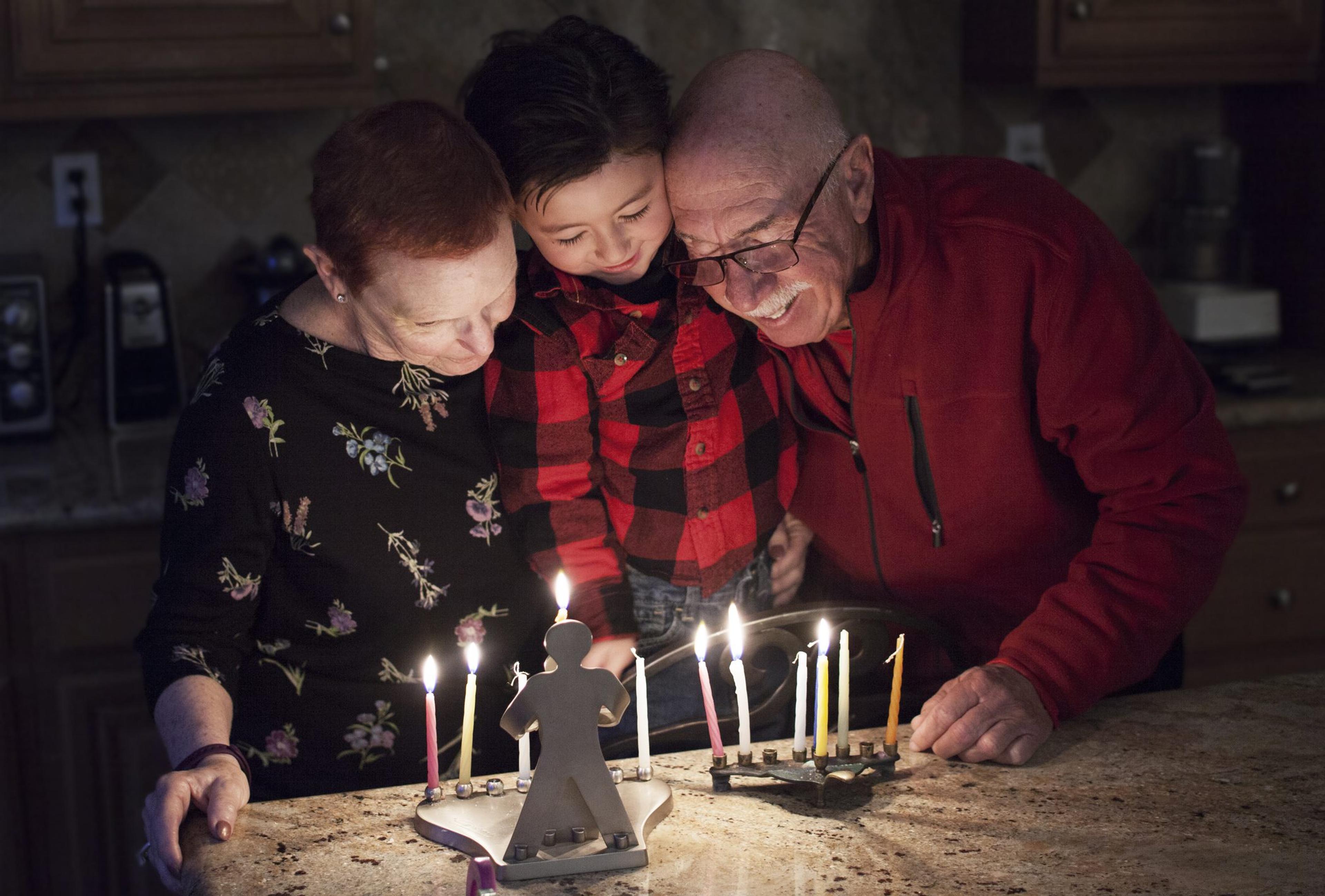 Jewish Family with granparents and grandson lighting Hanukkah Candles in a menorah for the holidays