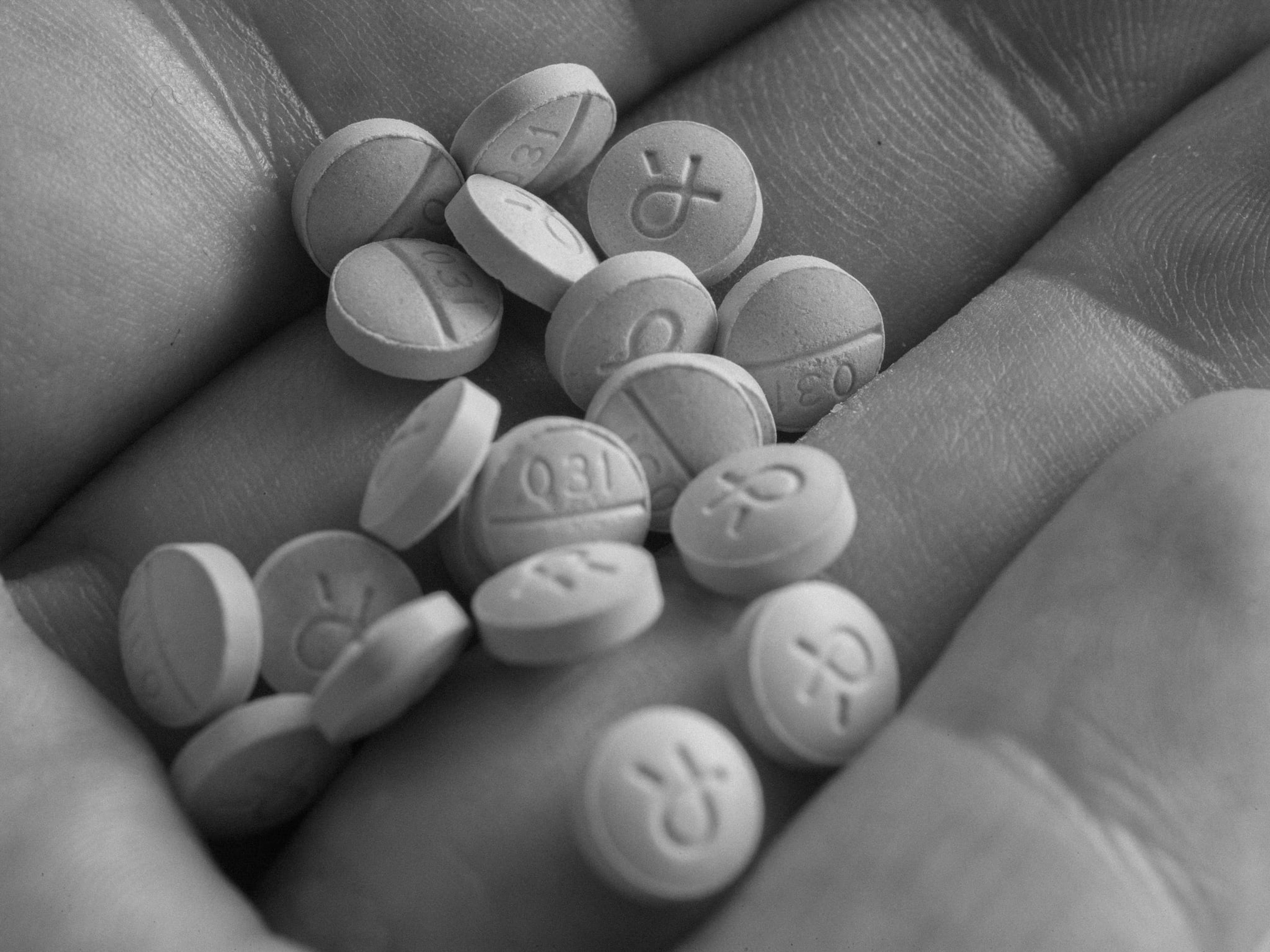 Black and white close-up of a hand holding pills.
