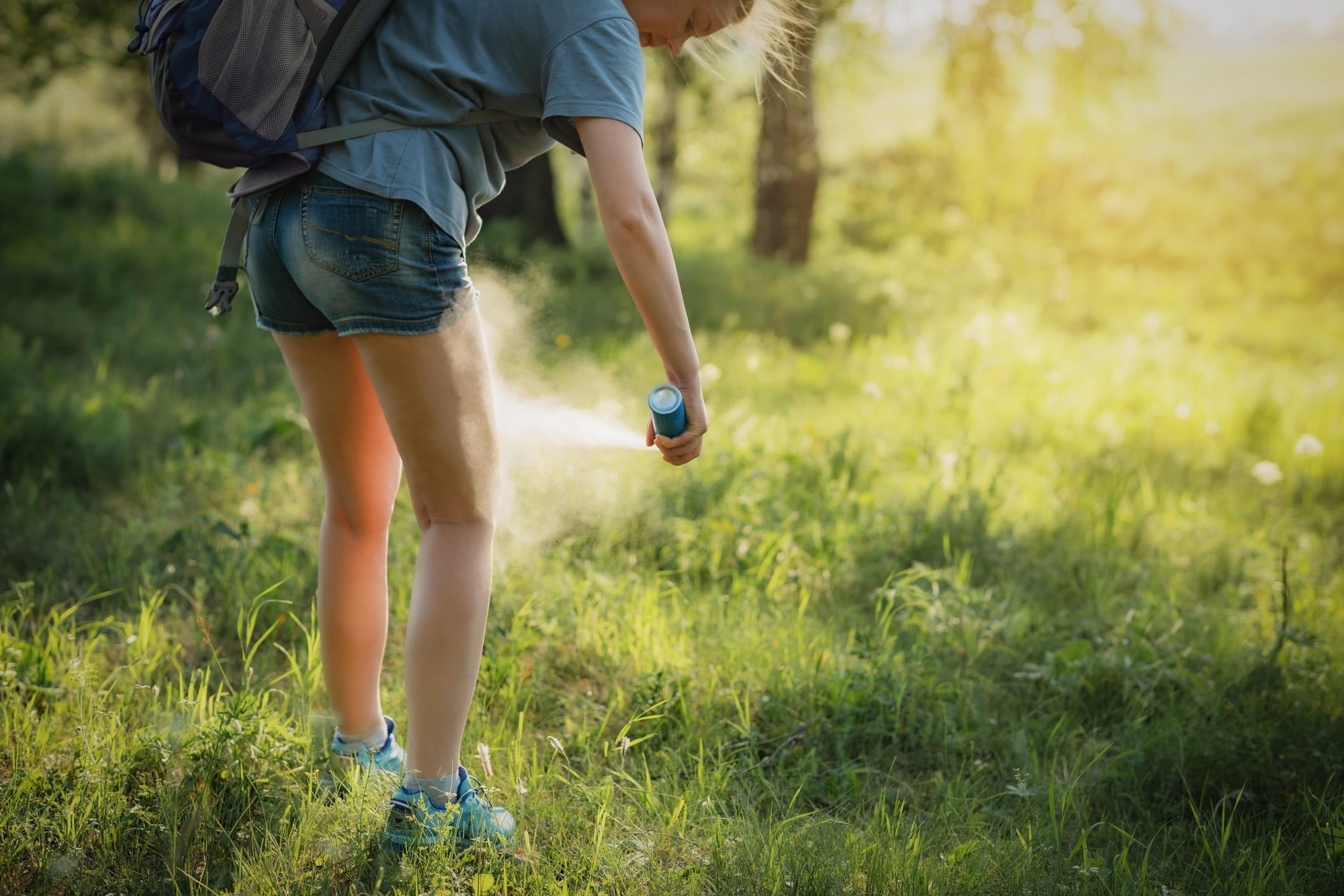 Teen spraying bug spray on legs