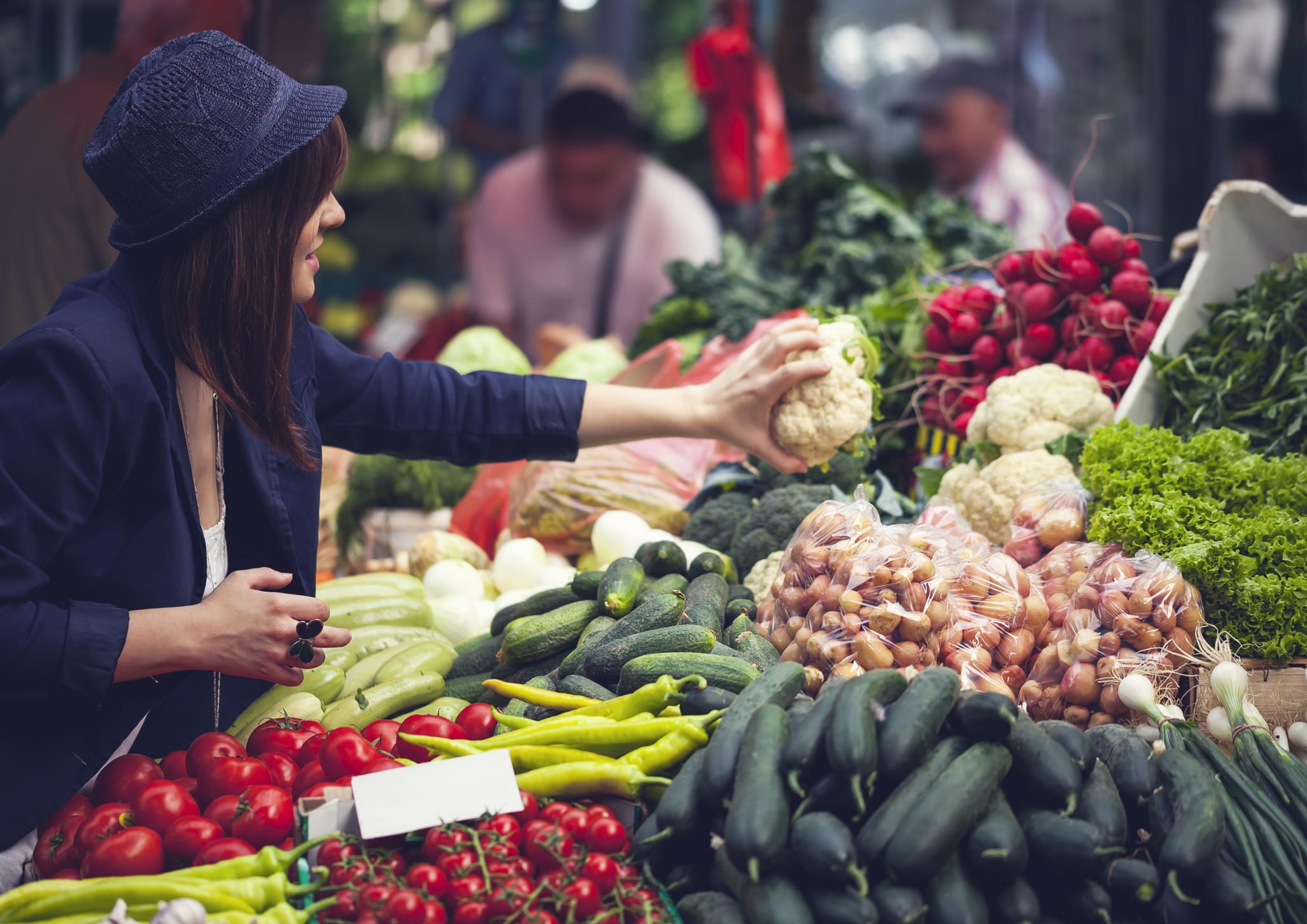 Young Female Choosing Vegetables At Market Place