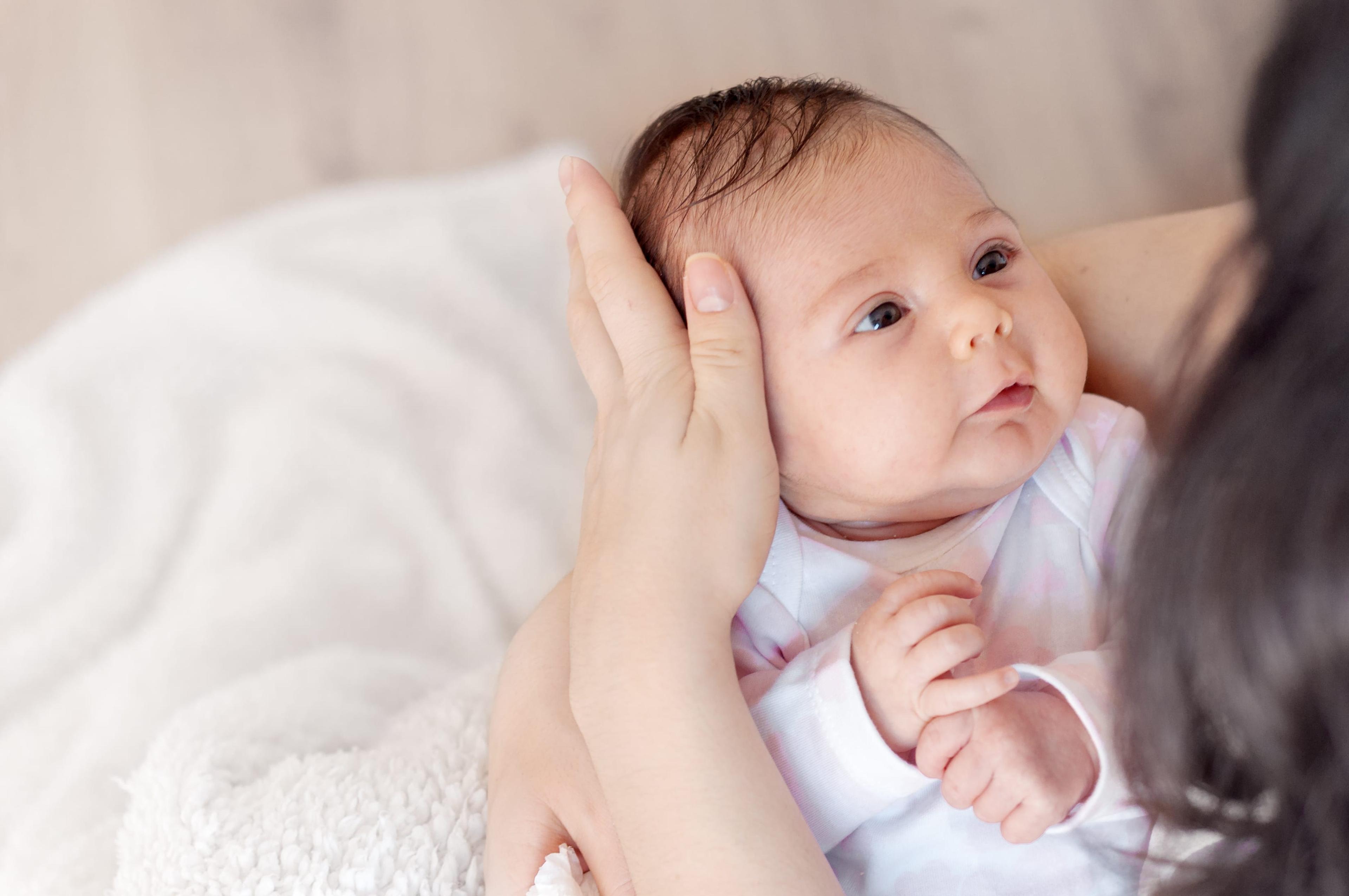 newborn baby looking up at her mom