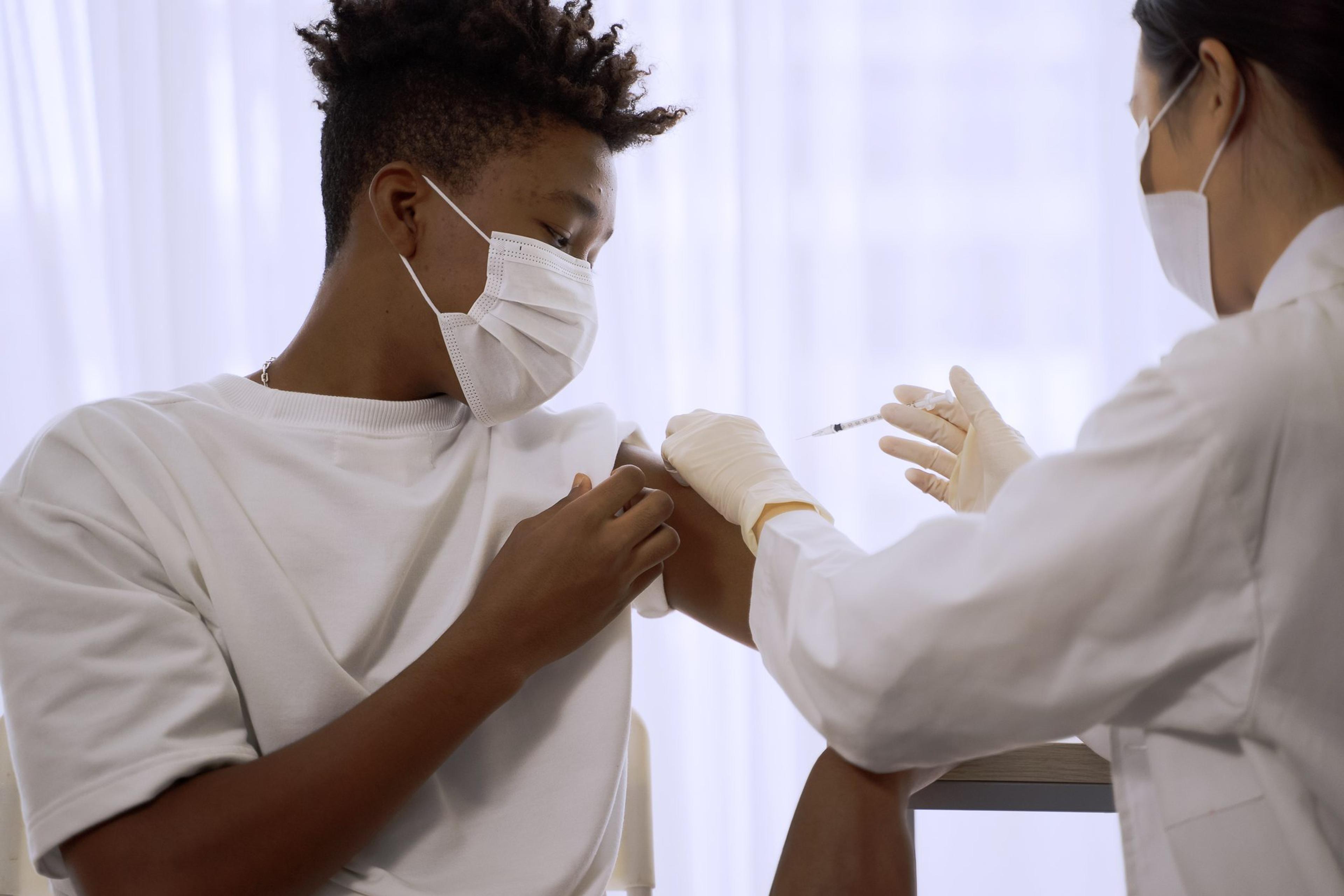 Young man receives a flu shot in his arm