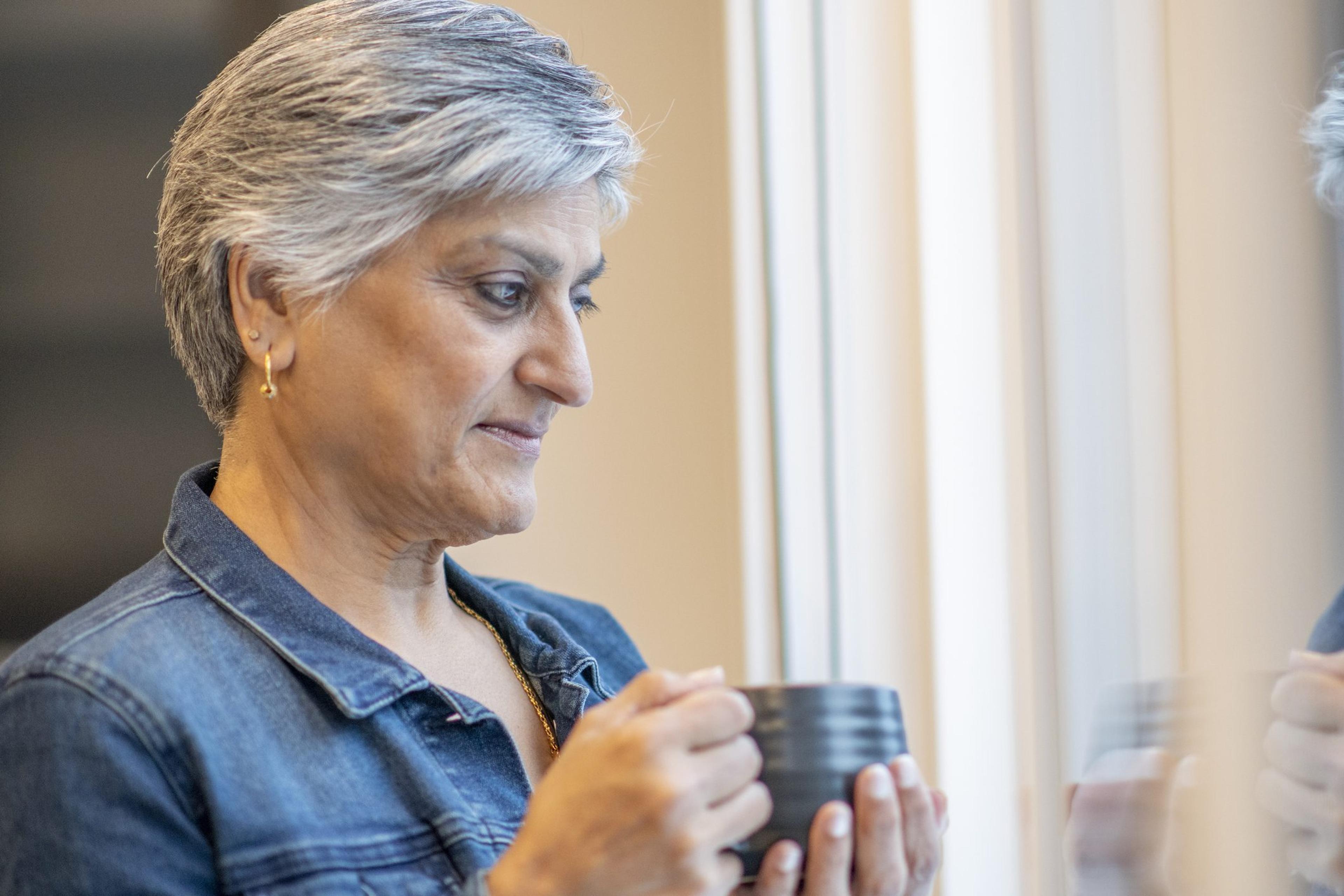 Older woman looks out the window wondering when to see a doctor for memory loss