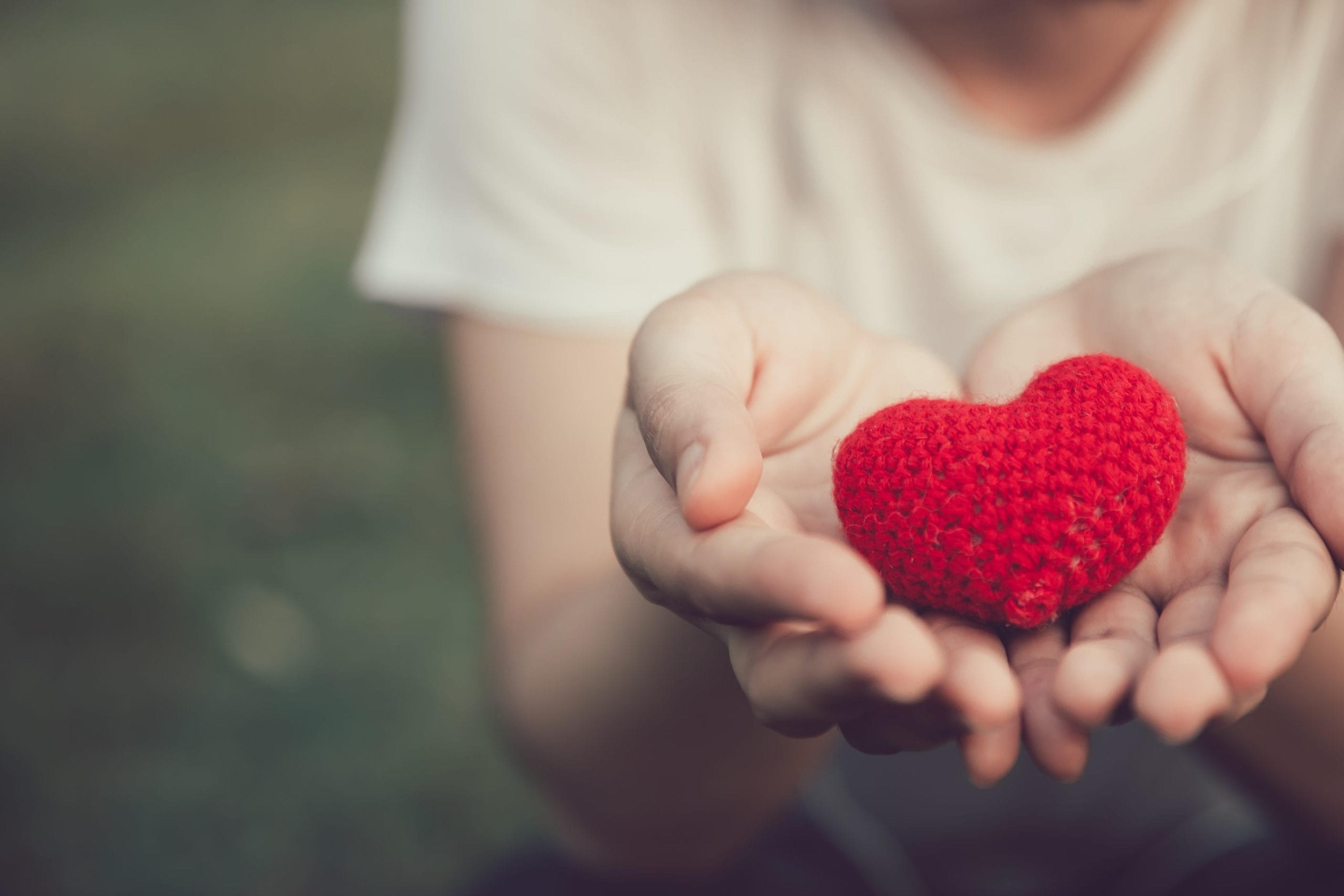 Woman holding a red crocheted heart in her hand.