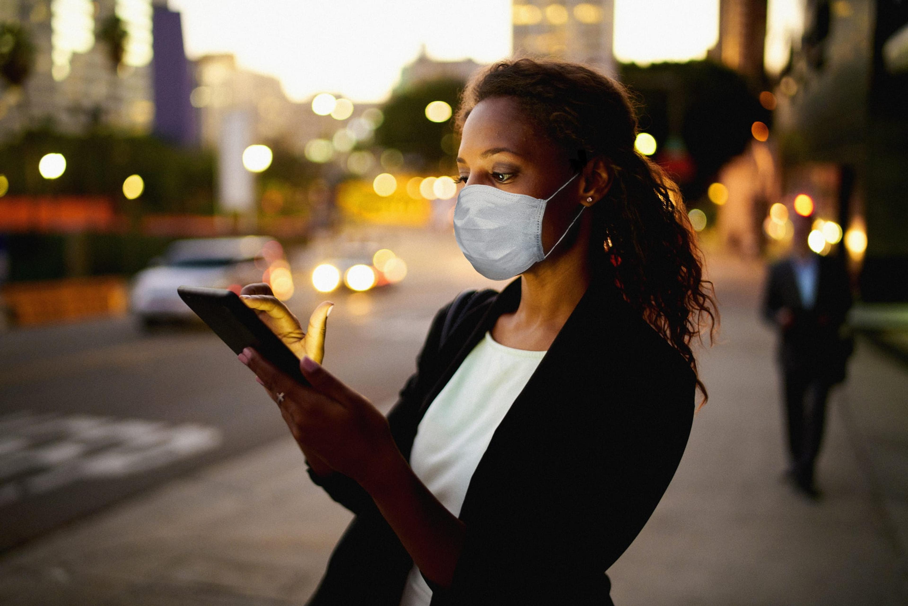 Woman wearing a mask looks at a tablet