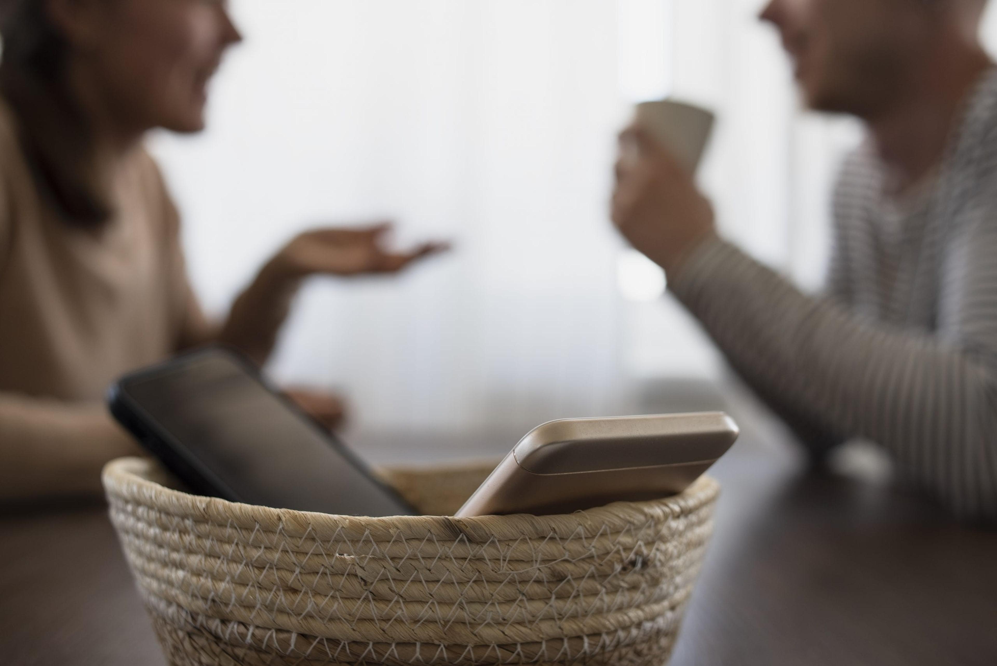 People on meeting without their phones. Digital detox concept. Turned off phones putting in basket