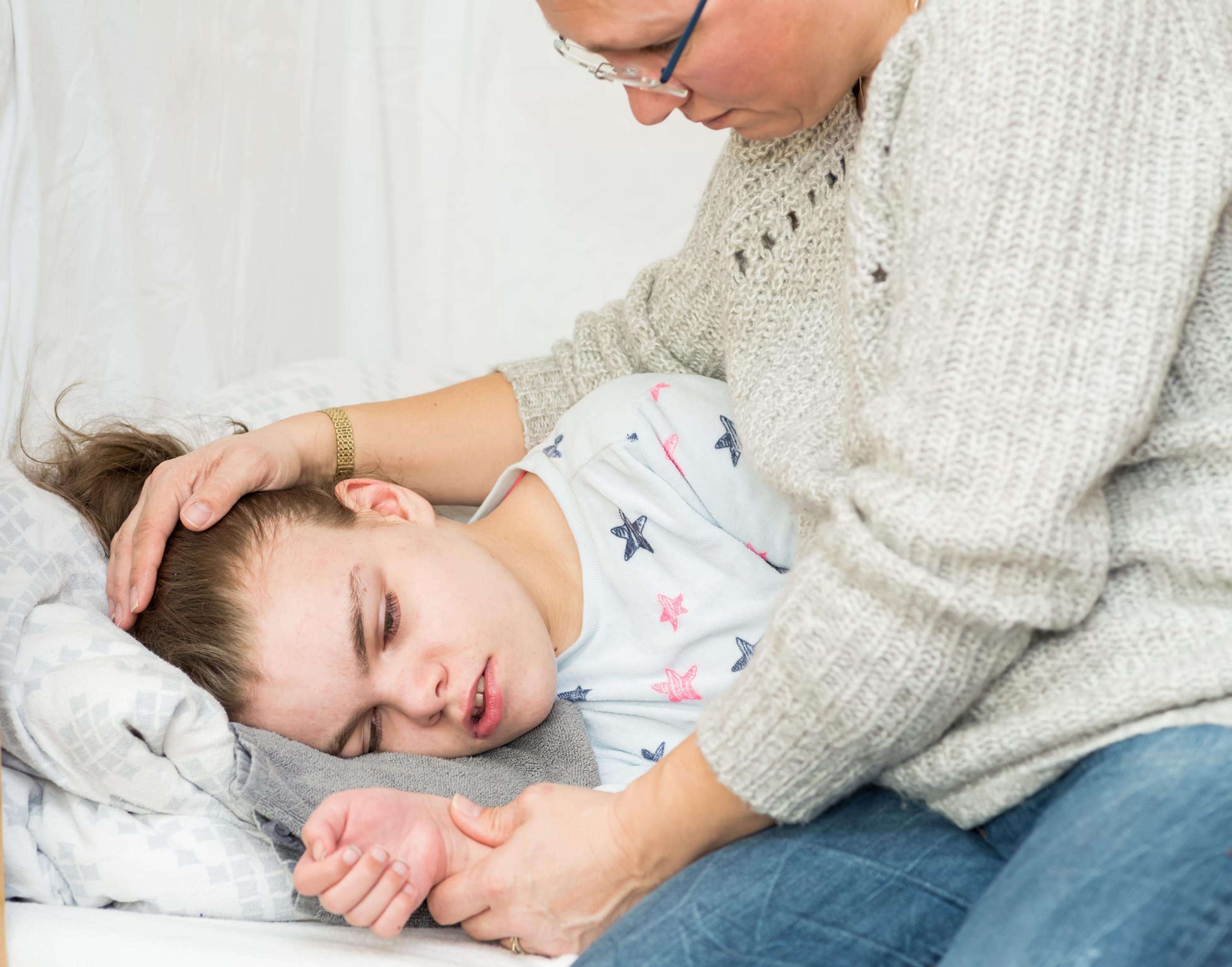Child experiencing an epileptic seizure is cared for by a caregiver