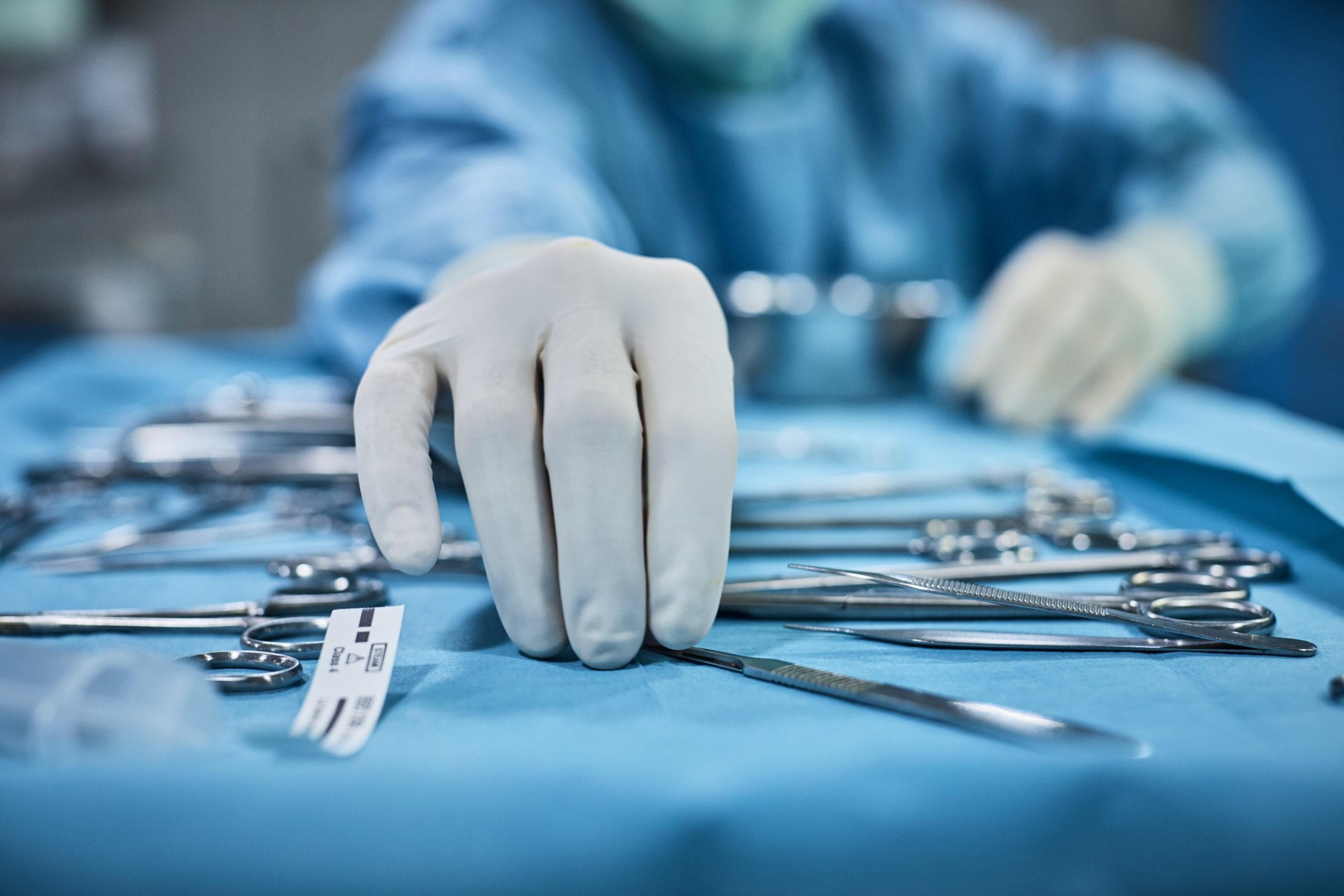 Surgeon's gloved hand reaching for an instrument