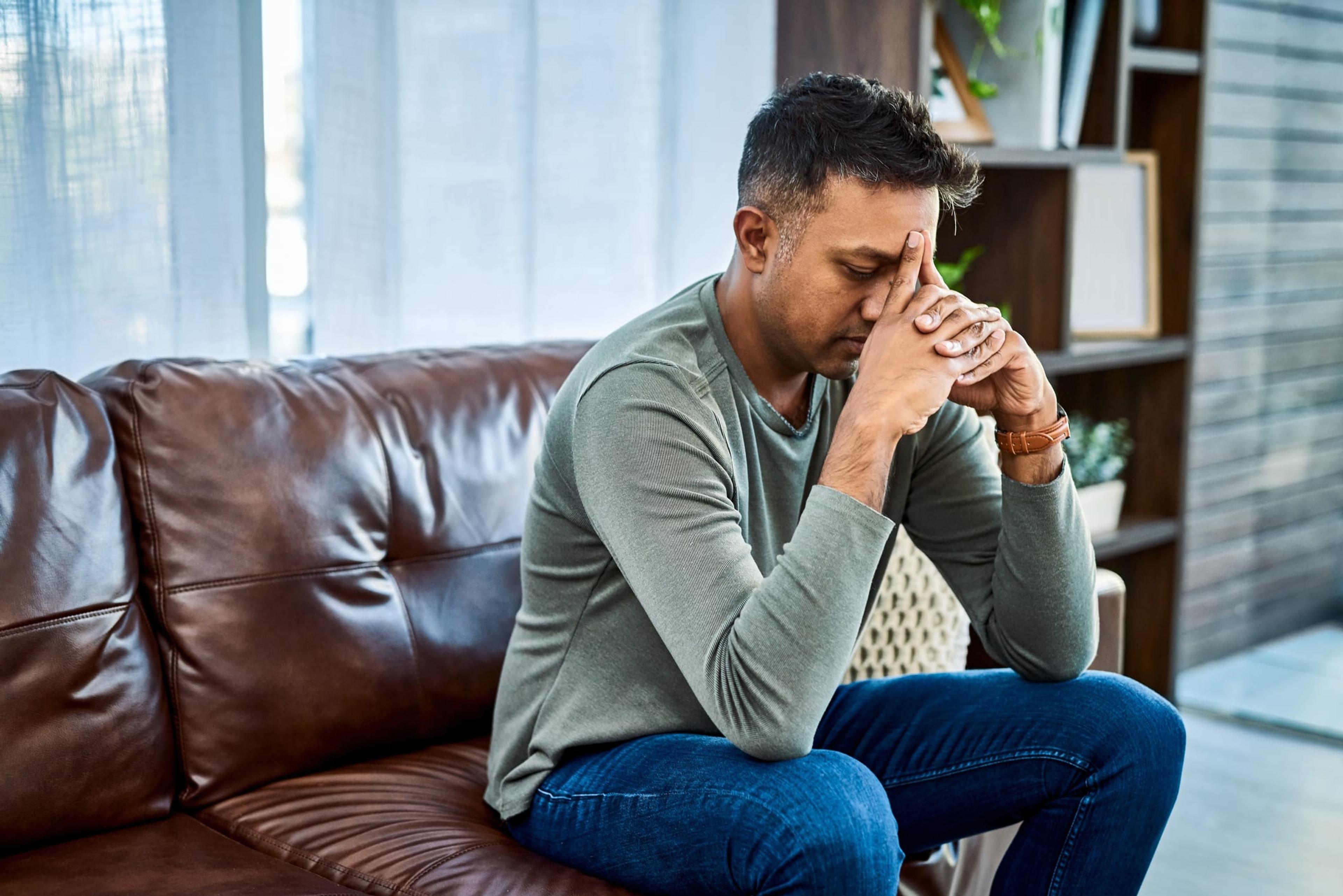 Men and mental health: man sits on the couch with his head in his hands