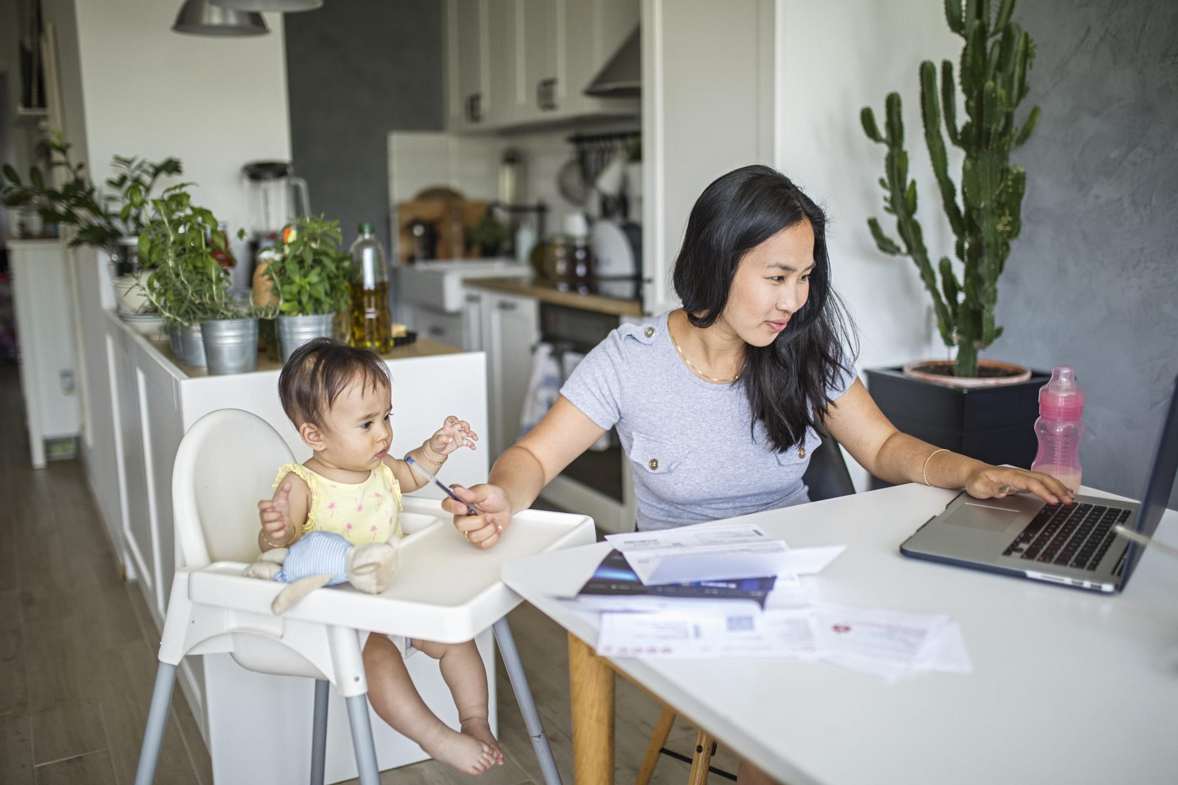 Woman working from home with baby in high chair