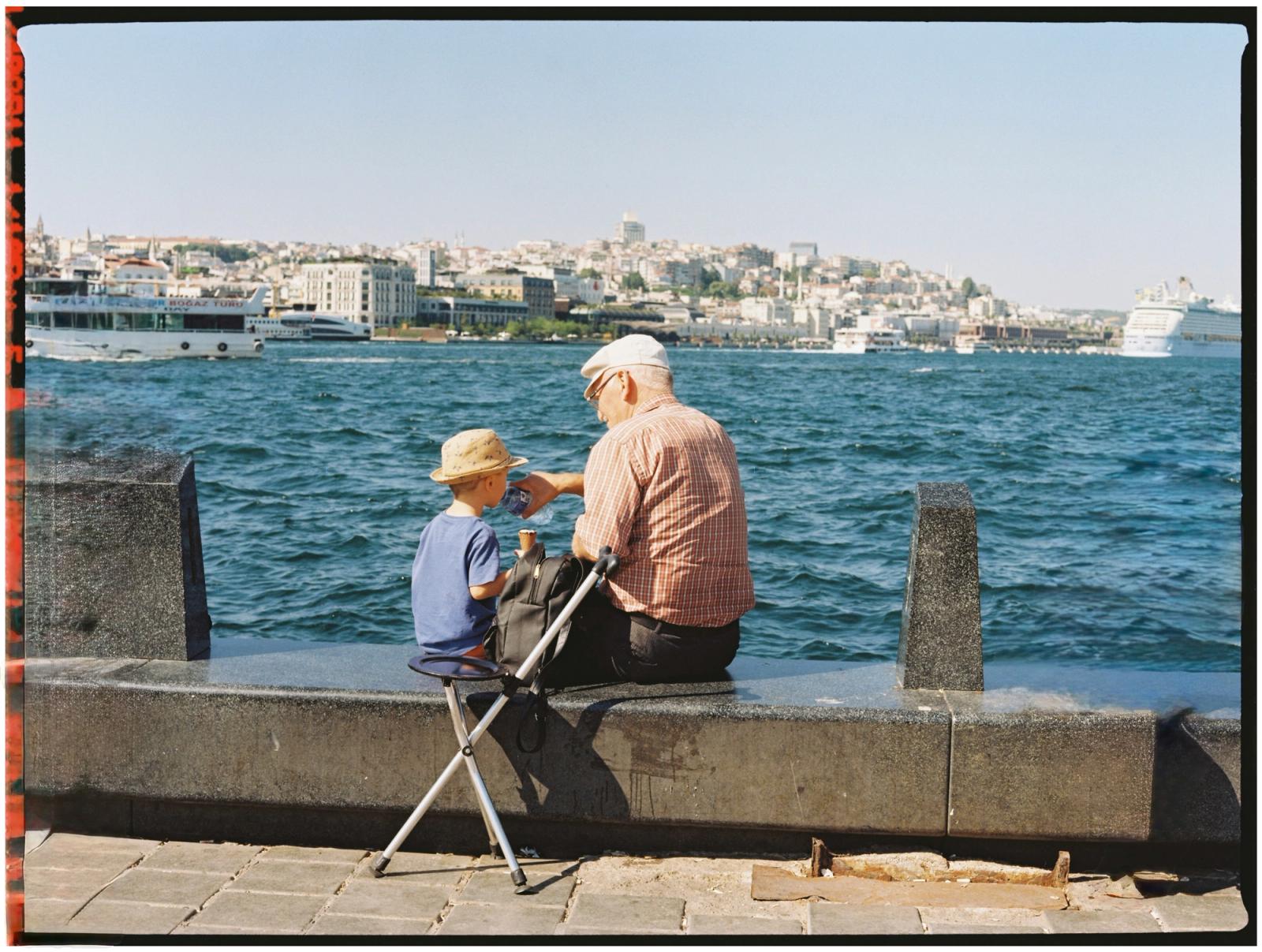 Old person looking at river with toddler