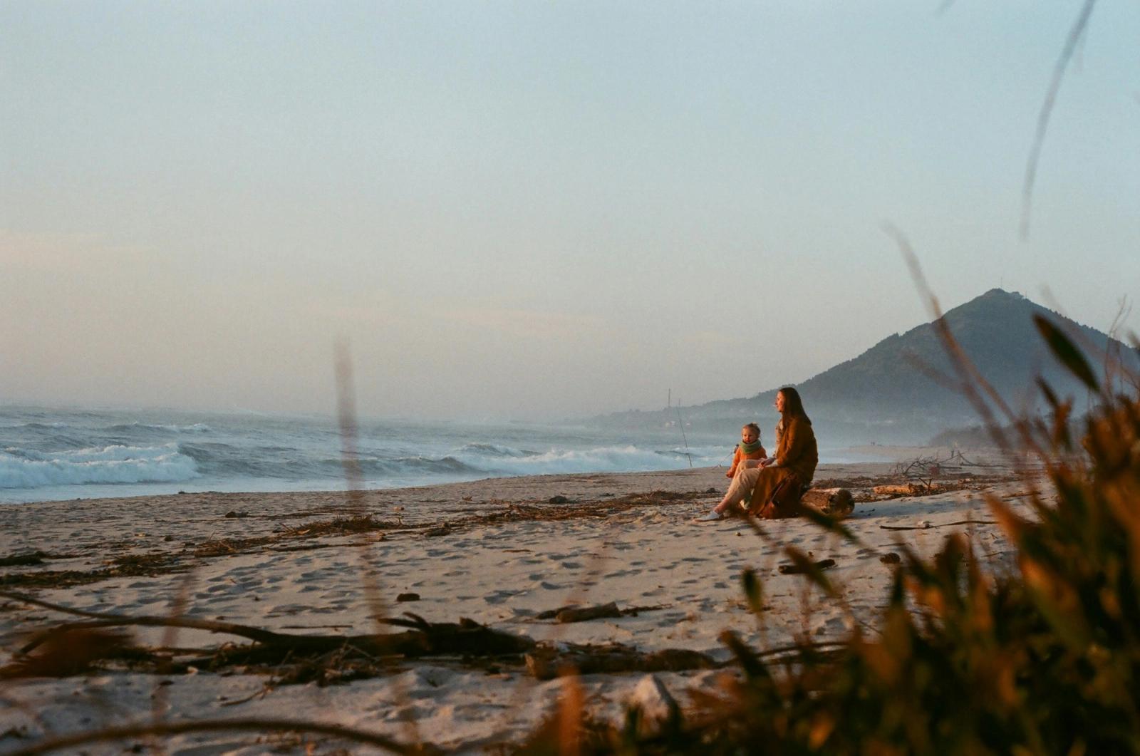 Mom and child on beach looking at ocean