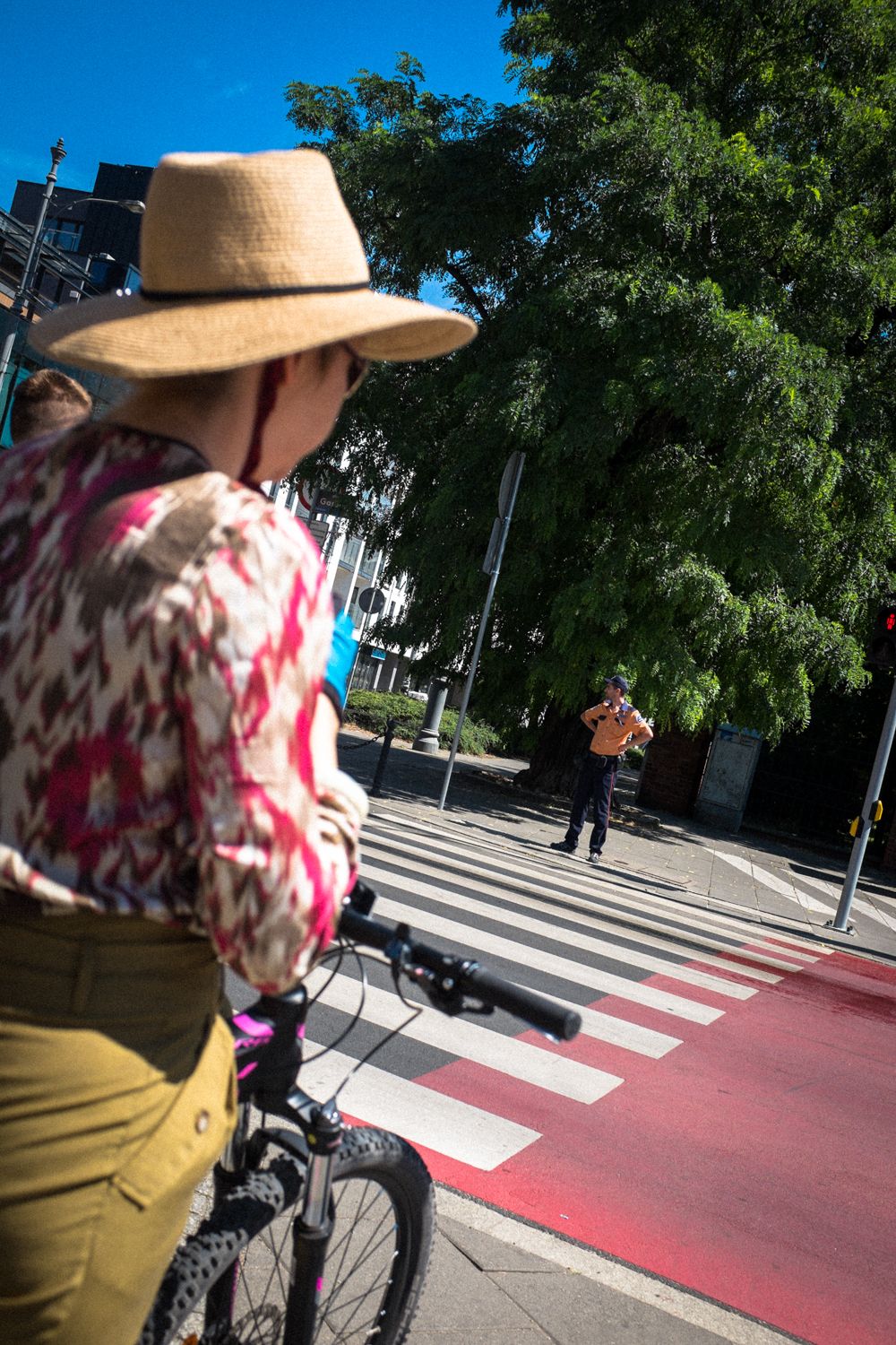 Straßenübergang mit Zebrastreifen in Posen. Im Vordergrund eine Frau mit Hut, auf der anderen Straßenseite wartet ein Mann.