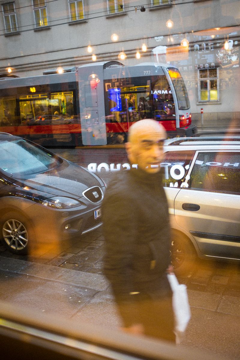 Coffee Blick aus einem Café in Wien. Auf der Straße fährt eine Straßenbahn vorbei, ein Mann geht auf dem Gehweg.