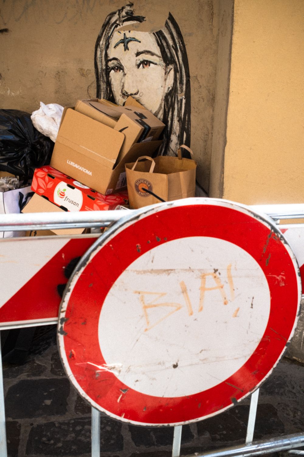 Hinter einem Müllberg und einem Verkehrsschild entdeckt man Streetart in den Straßen von Florenz.