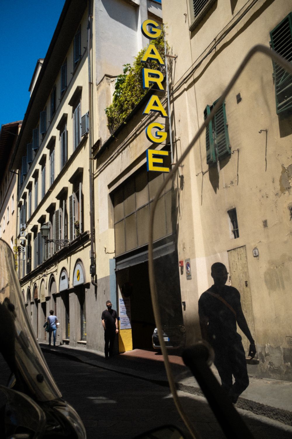 Garage in der Altstadt von Florenz. Starke Licht-Schatten-Kontraste lassen sich die Fassade von den Fußgängern auf der Straße abheben.