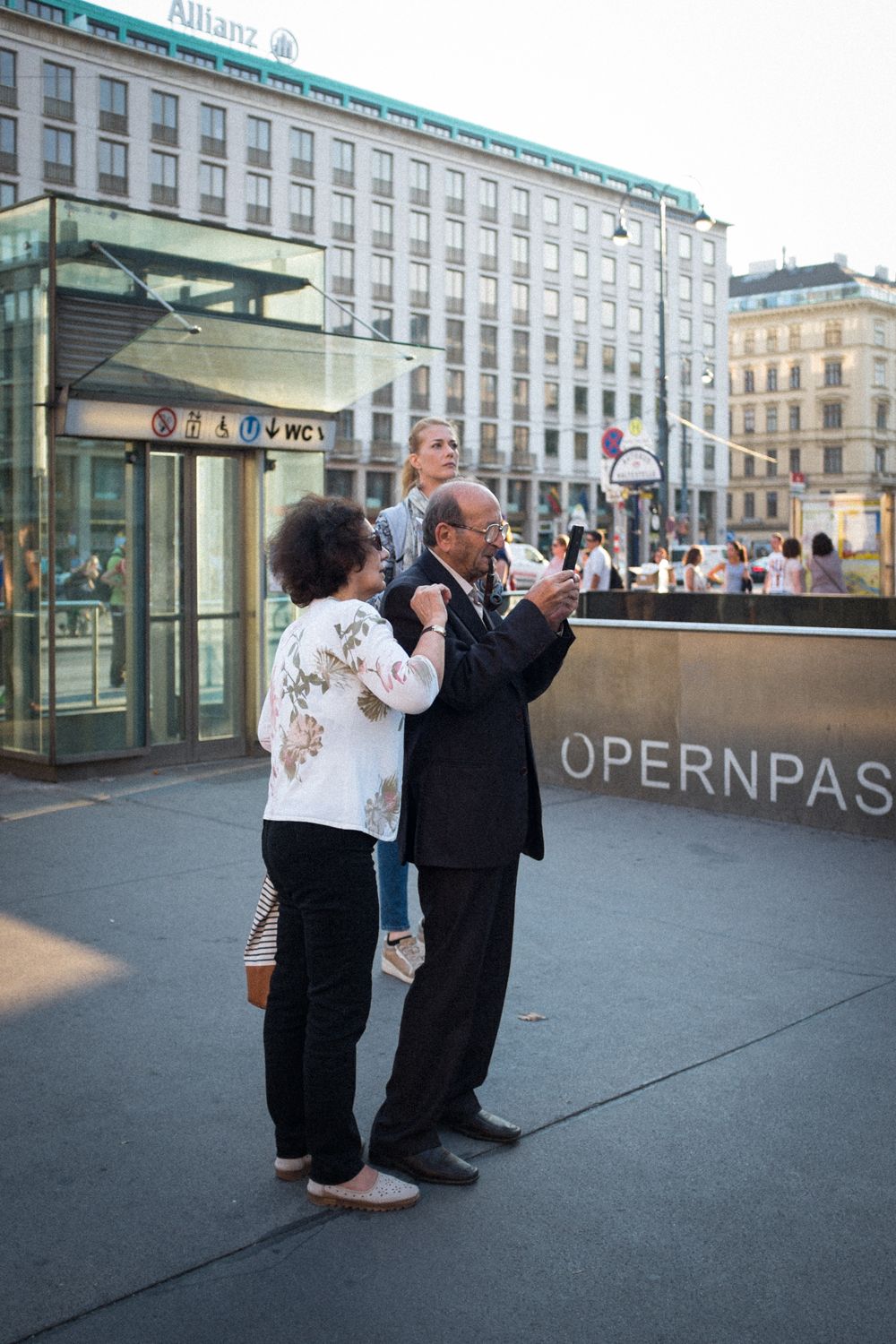Straßenfotografie vor der Wiener Oper - ein Ehepaar schaut auf ein Smartphone