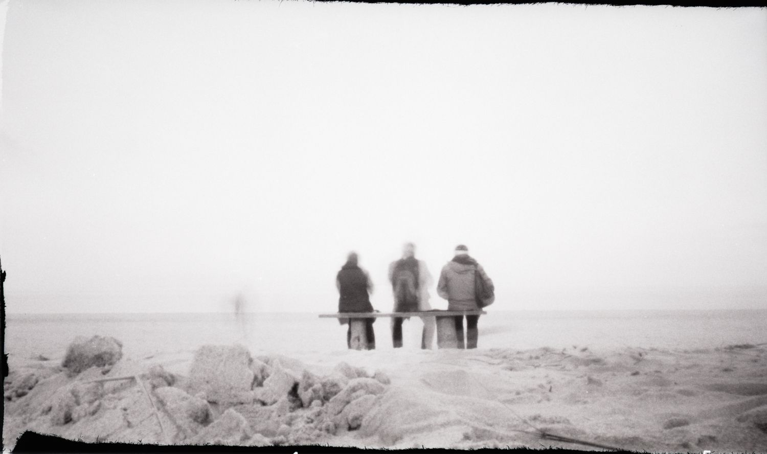 Auf einer Bank Sitzende, auf das Meer blickende Menschen an der Ostsee mit der Lochkamera aufgenommen.