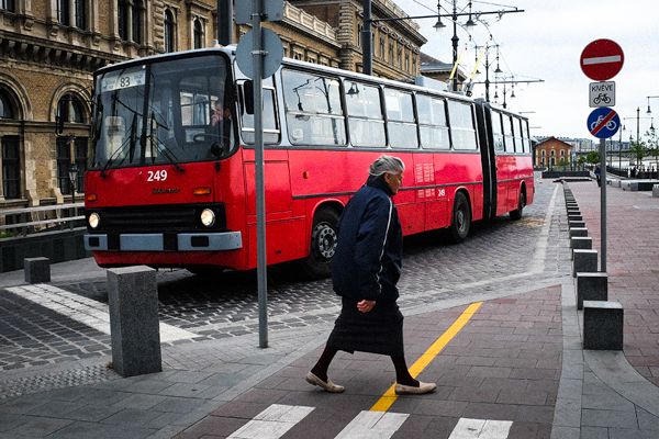 Street Photography Budapest Street Photography aus Budapest, der Hauptstadt Ungarns. Eine Rentnerin überquert die Straße. Ein Ikarus Bus lässt sie passieren. Der Ikarus Bus wird in Ungarn hergestellt und ist in vielen ehemals kommunistischen Ländern weit verbreitet.