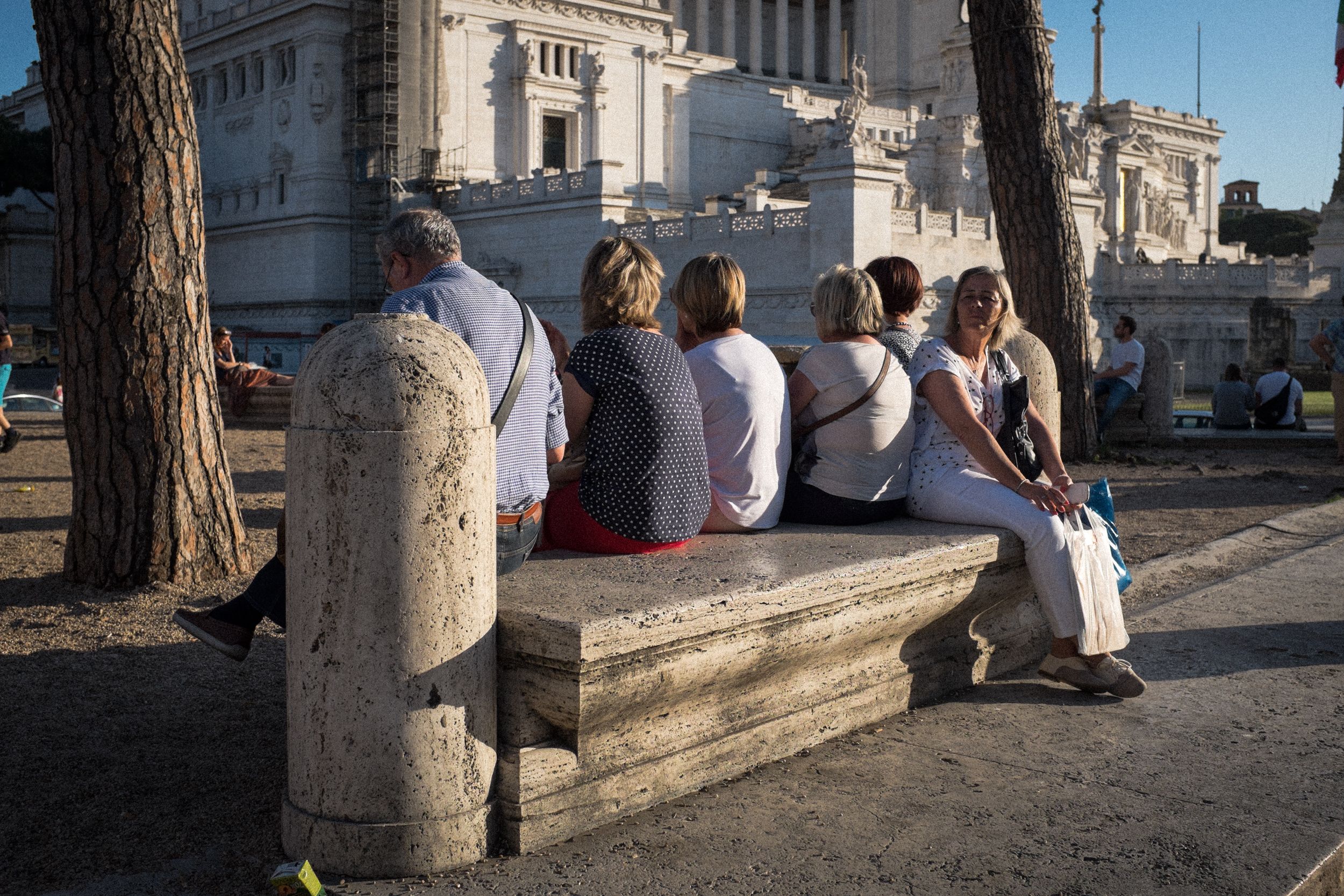 Menschen sitzen vor dem Monumento Vittorio Emanuele II an der Piazza Venezia. Das Gebäude wird aufgrund seiner Form im Volksmund Schreibmaschine genannt.