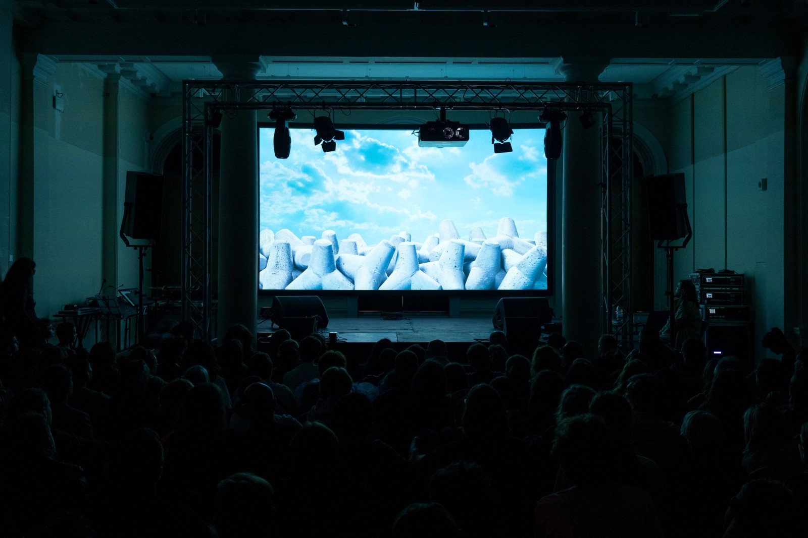 Film screening to a seated audience under a truss-hung projection screen, Assembly 2024, Somerset House Studios